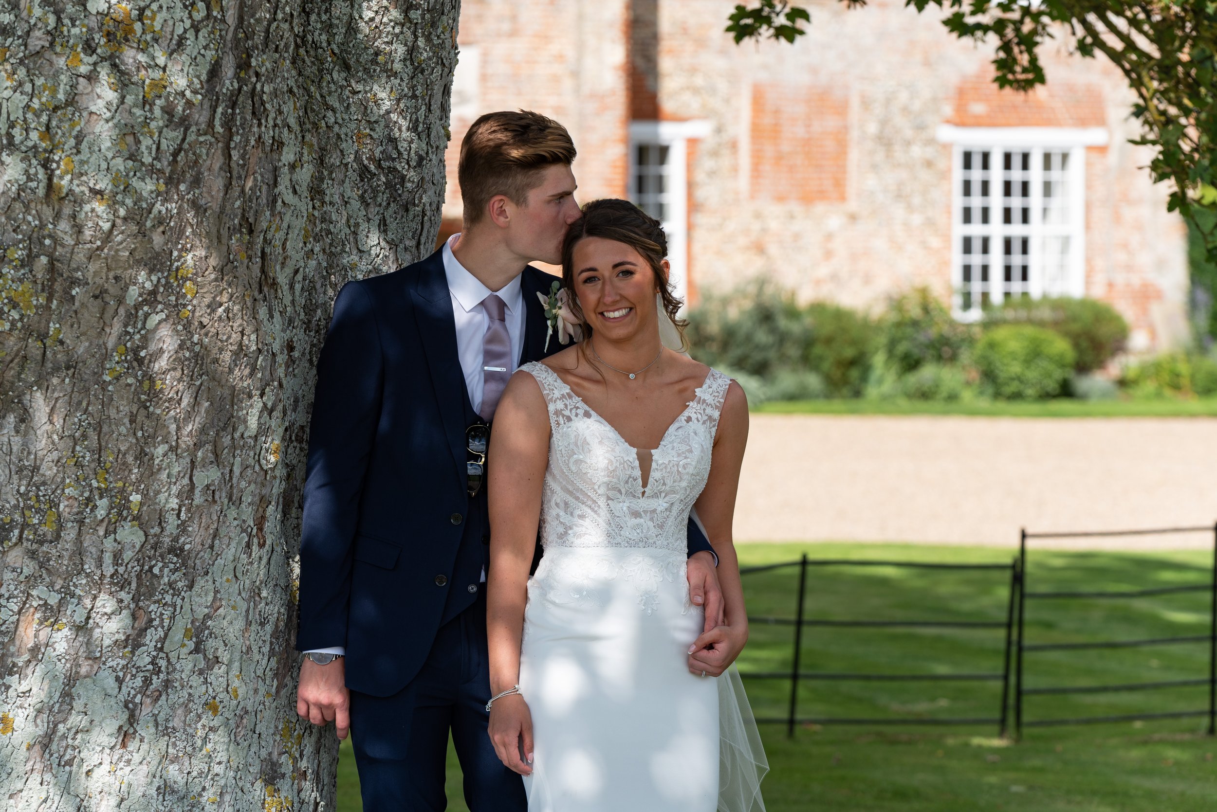  bride and groom posing by tree 