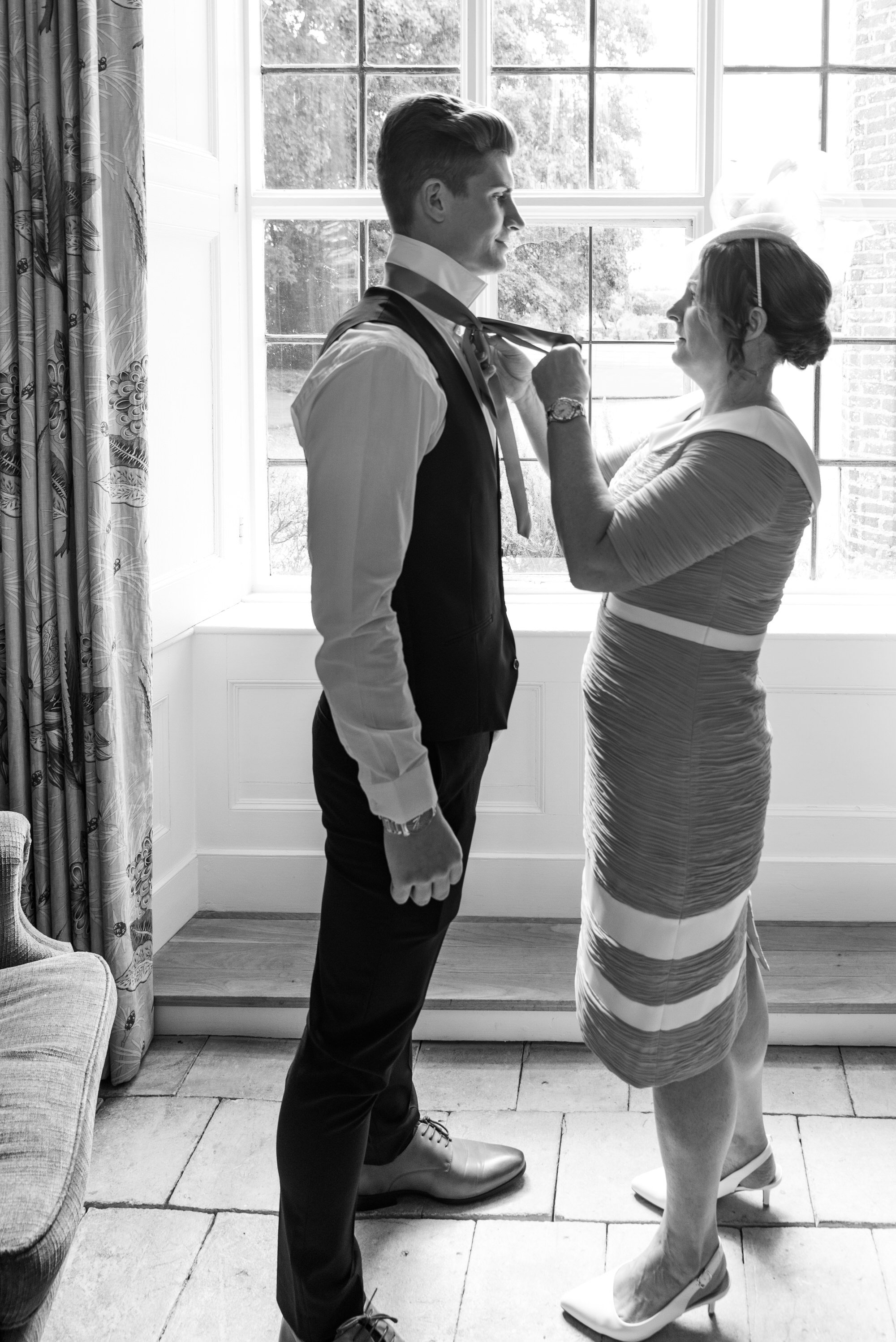  mother of groom tying his tie for wedding 