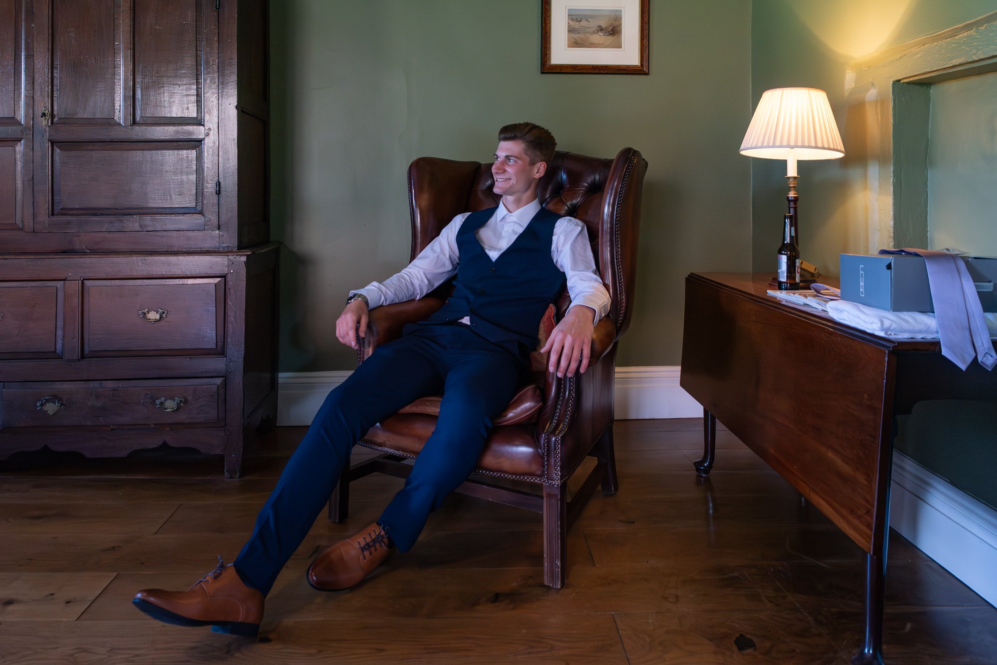  groom relaxing in Chesterfield chair 