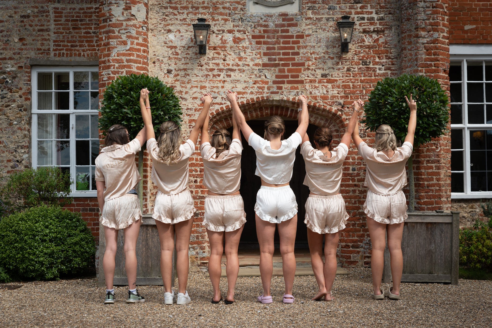  bridal party holding hands in air in front of suffolk wedding venue 