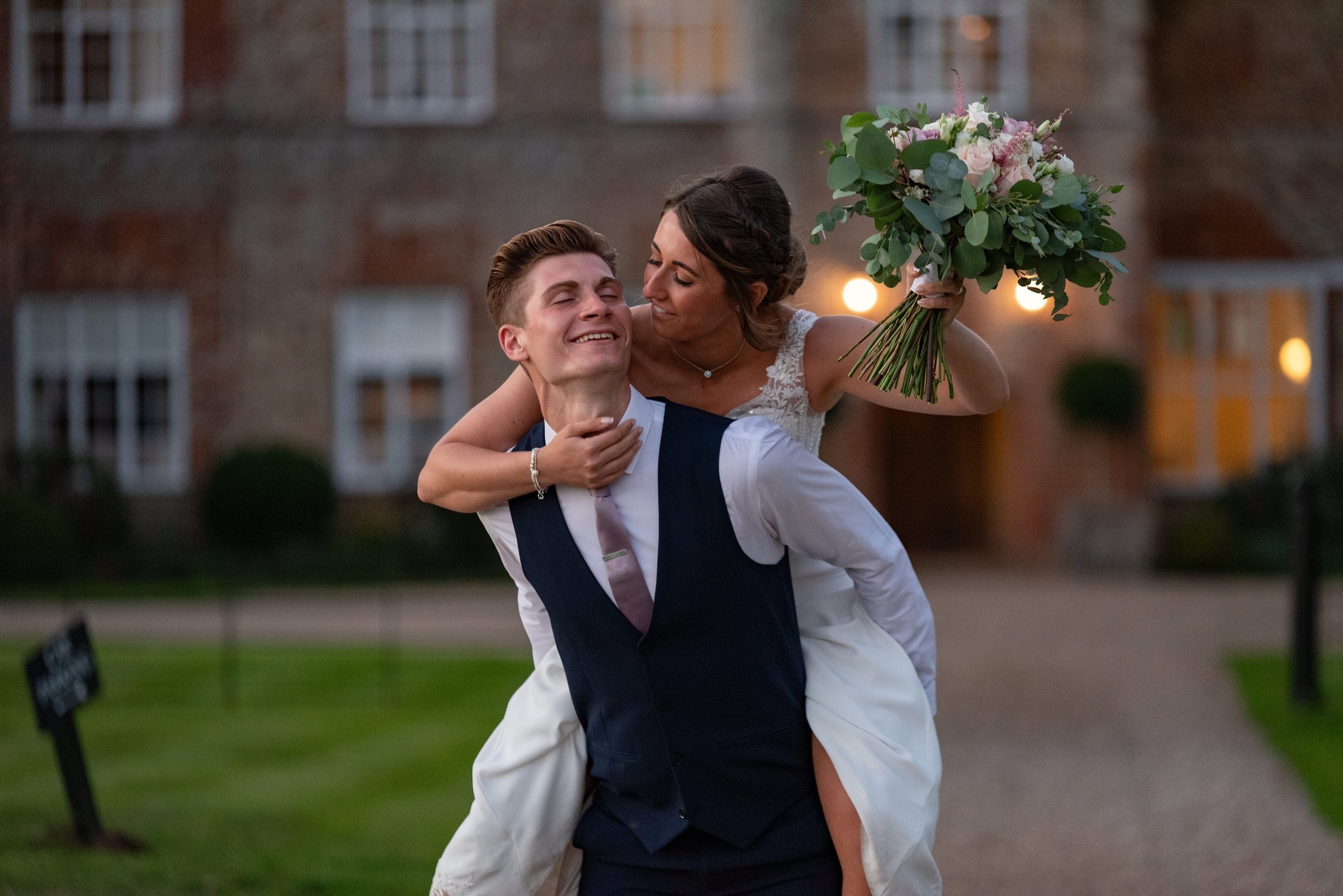  bride and groom enjoying a piggyback at dusk in grounds of Bruisyard Country Estate 