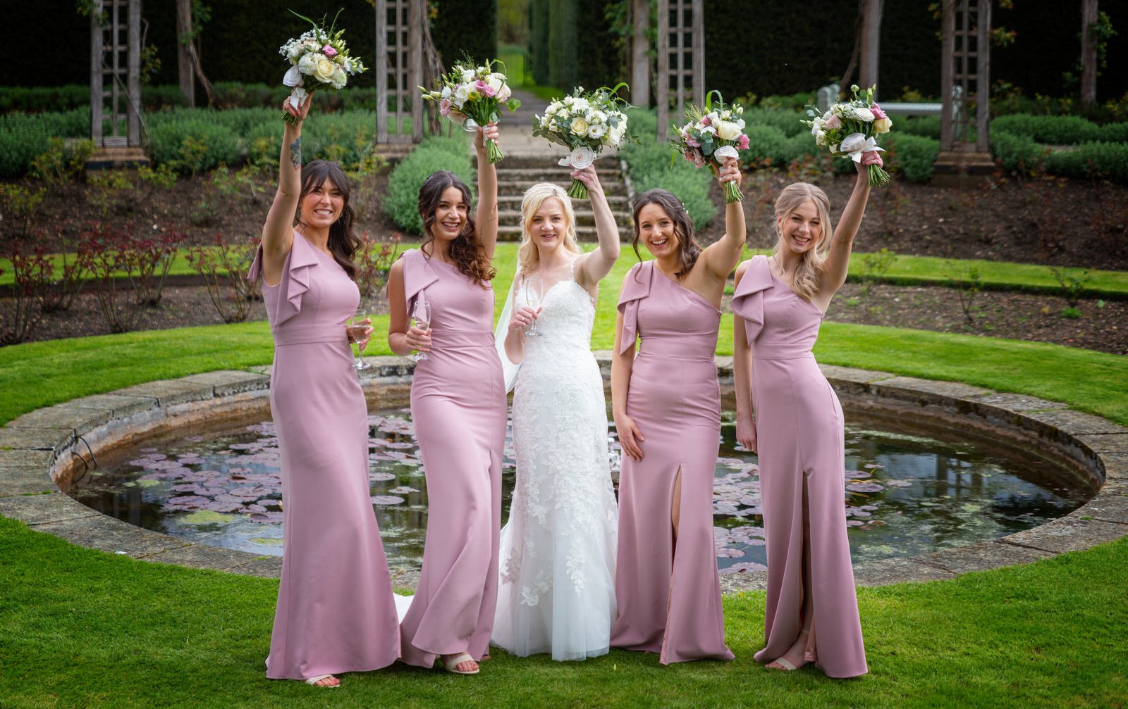 bride-bridesmaids-raising-bouquets-great-fosters-gardens.jpg
