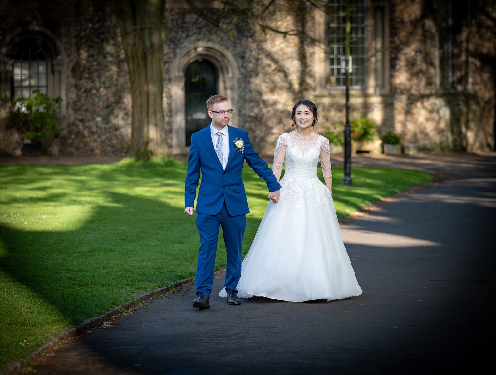 bury-st-edmunds-cathedral-grounds-wedding-couple-walk-holding-hands.jpg