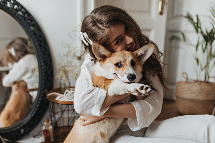 brunette-woman-smiling-hugging-corgi-happy-young-curly-lady-white-blouse-has-fun-with-cute-dog-cozy-room copy.png