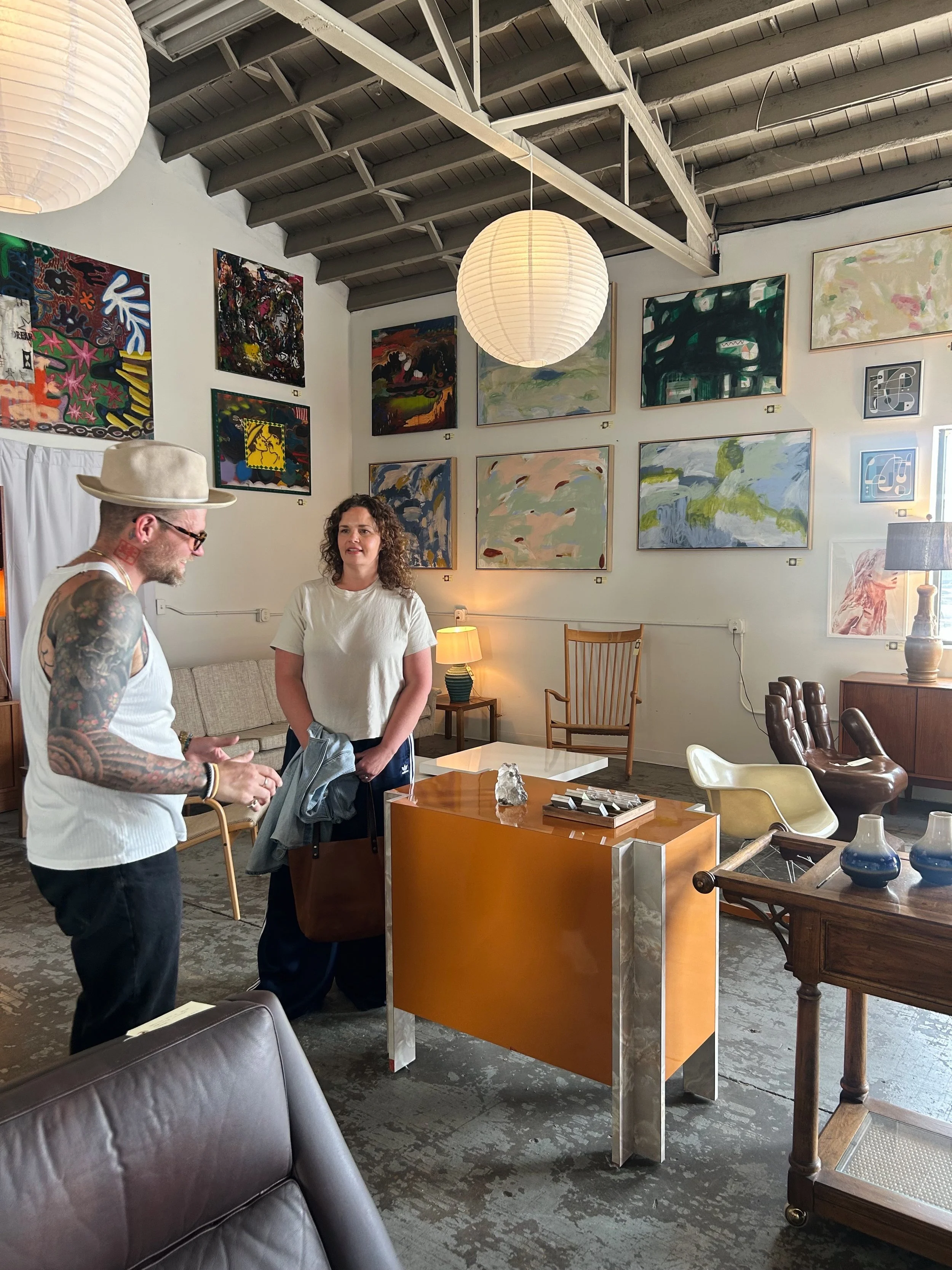 artist Amy Early with Herron Home business owner Mason Herron conversing amongst art and vintage furniture