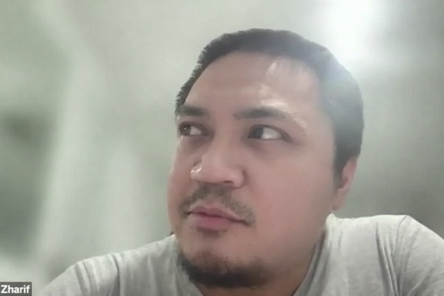 A man with short dark hair, facial hair, and light to medium skin tone looking to his left in a close-up portrait.