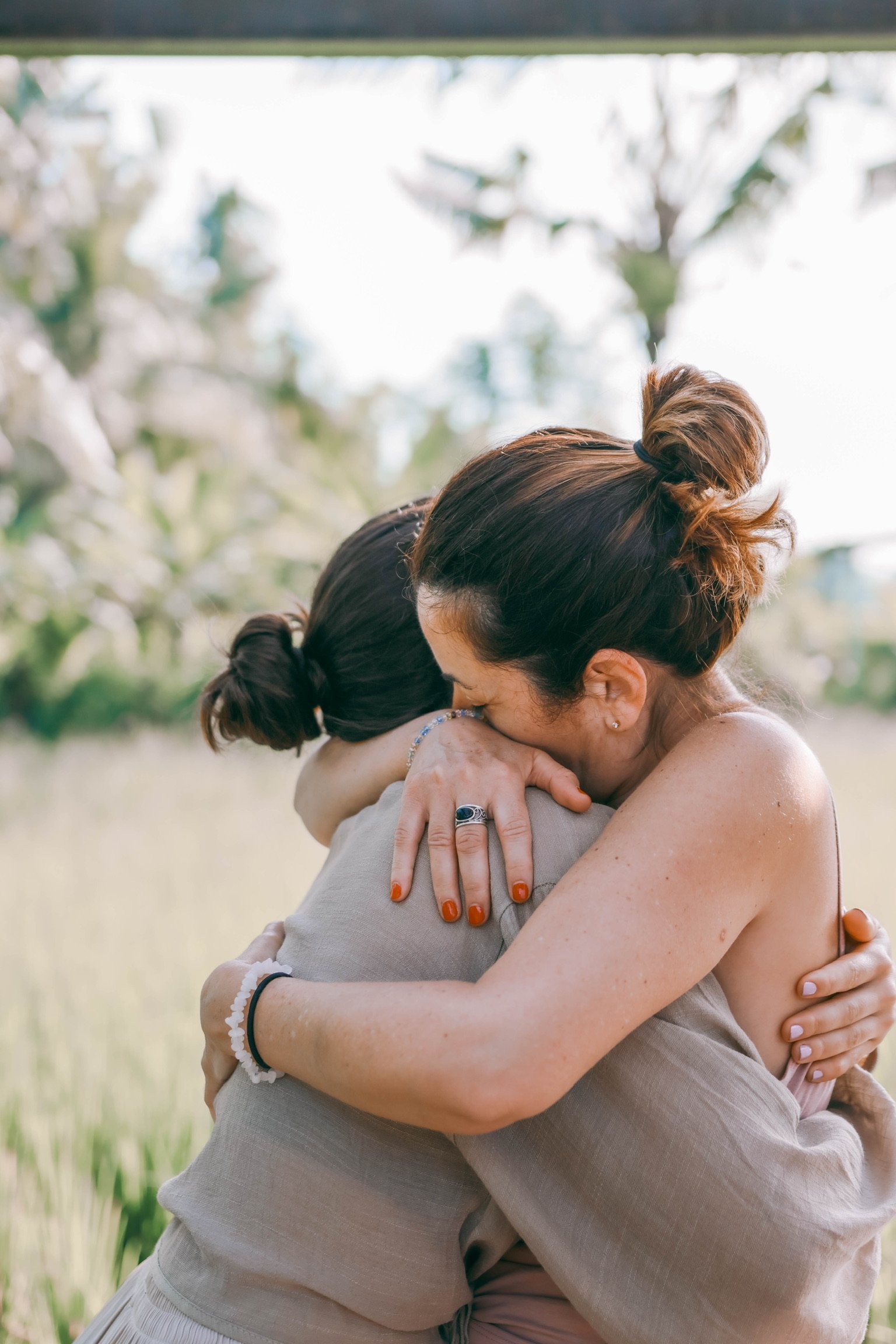 Dos mujeres se abrazan en un campo de flores, expresando amor y afecto.