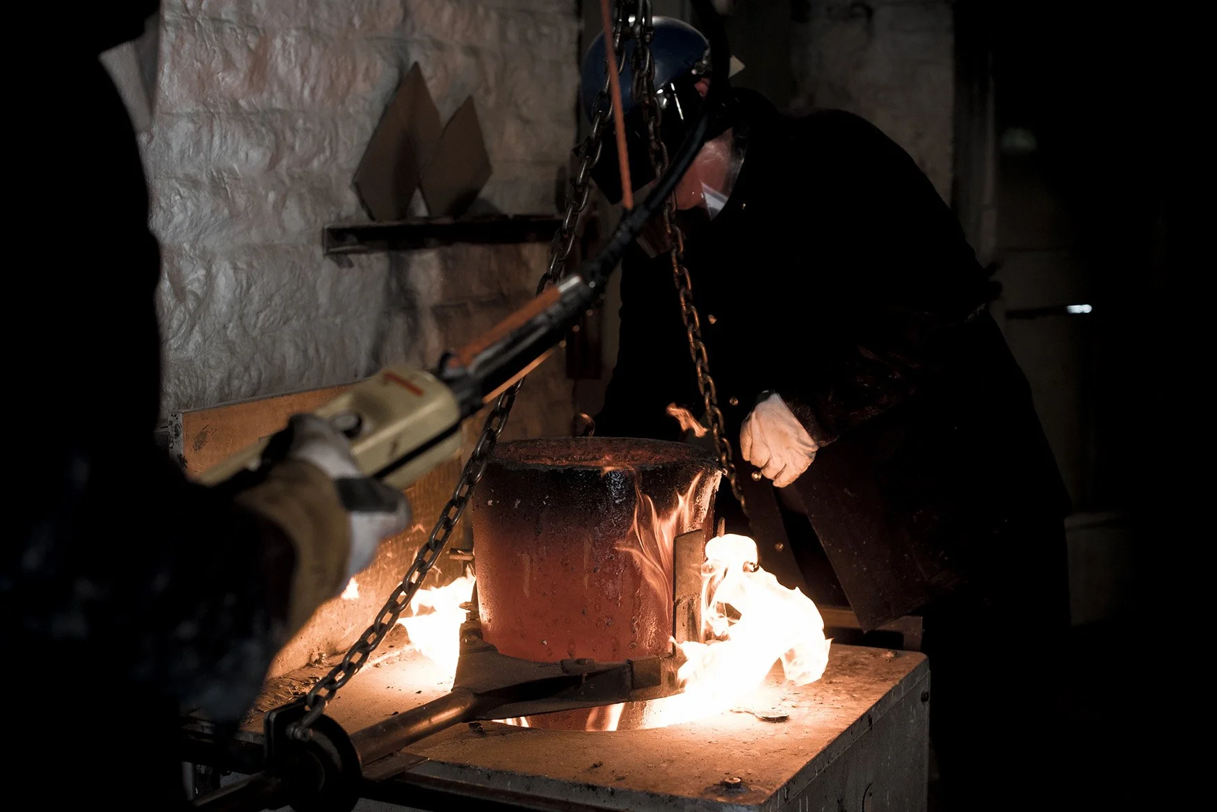 Foundry craftsman work with red hot crucible on flames