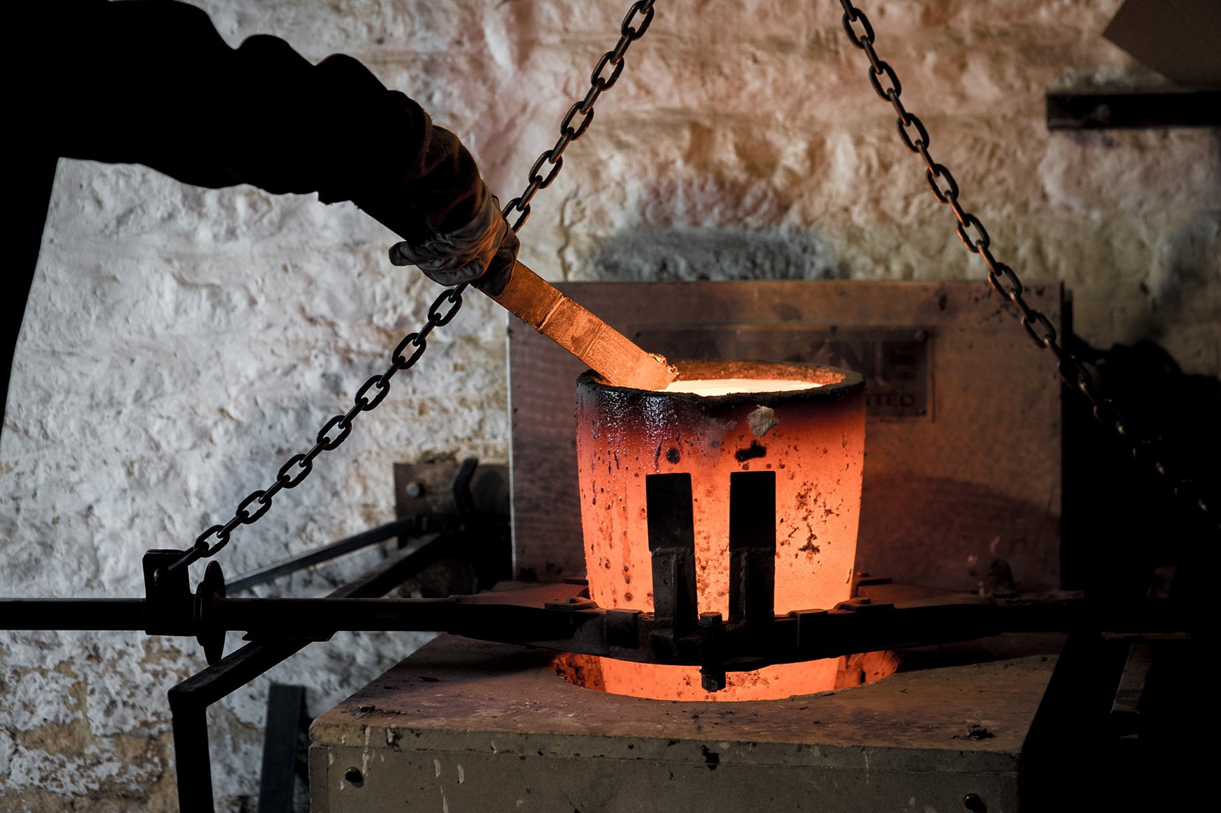 Foundry worker checking red hot crucible