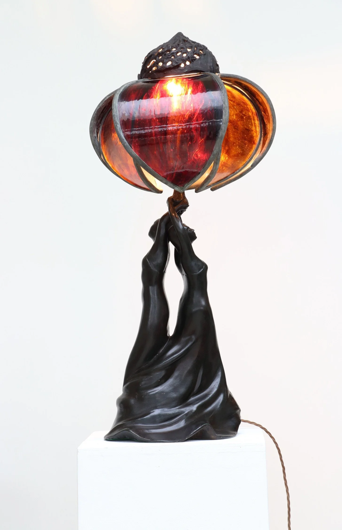Deco Lamp bronze sculpture two female figures material of long dresses swirled together arms raised and entwined holding up bronze and coloured glass petal shaped lampshade