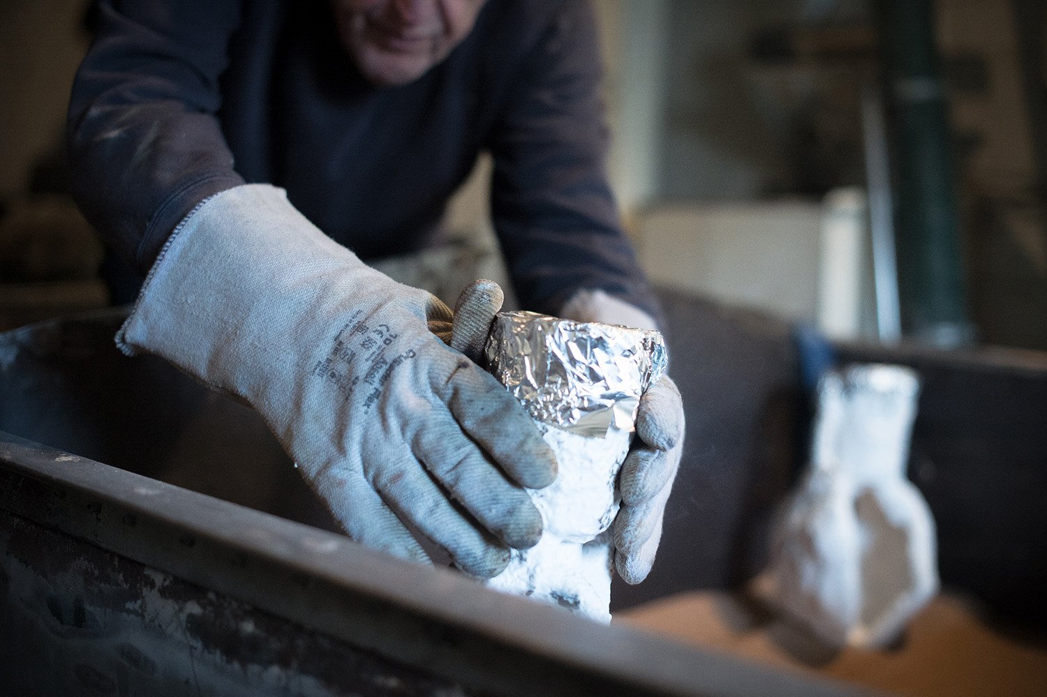 Foundry person prepares moulds in protective gloves
