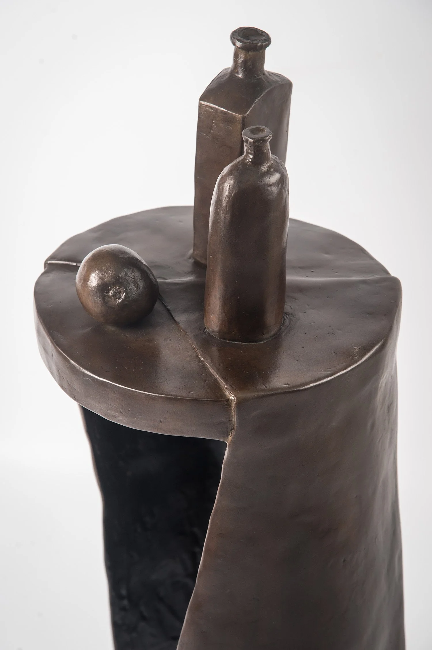 Still Life XIV life size bronze sculpture a pear and bottles placed on circular surface draped with a cloth close up view