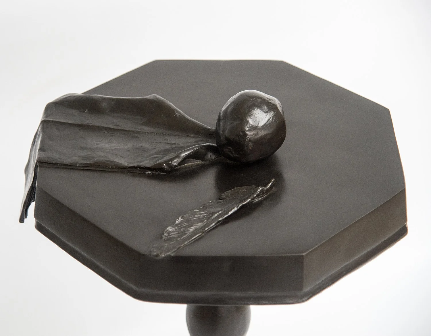 Still Life V life size bronze sculpture of cloth apple and feather on octagonal table close up view