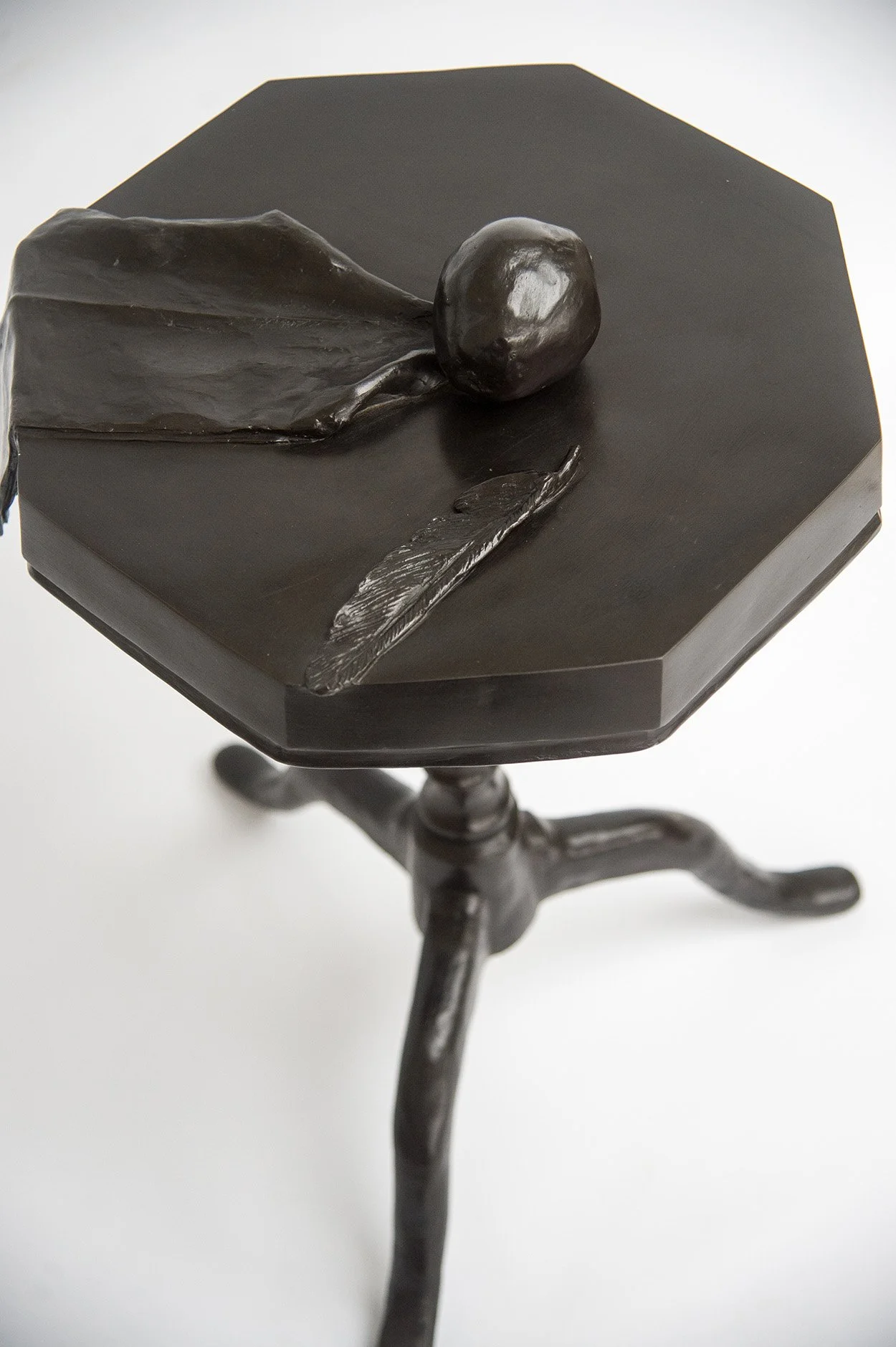 Still Life V life size bronze sculpture of cloth apple and feather on octagonal table above view