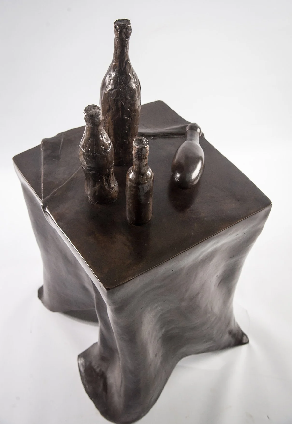 Still Life VII life size bronze sculpture of table draped tablecloth and bottles