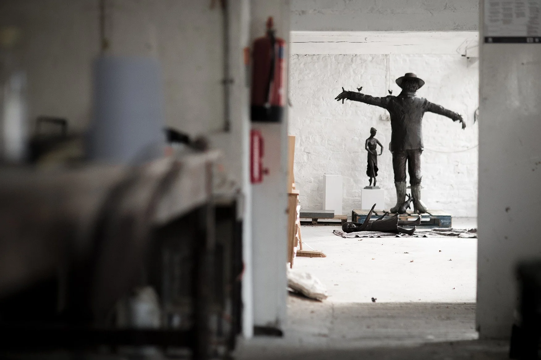 View through foundry bronze scarecrow sculpture in studio