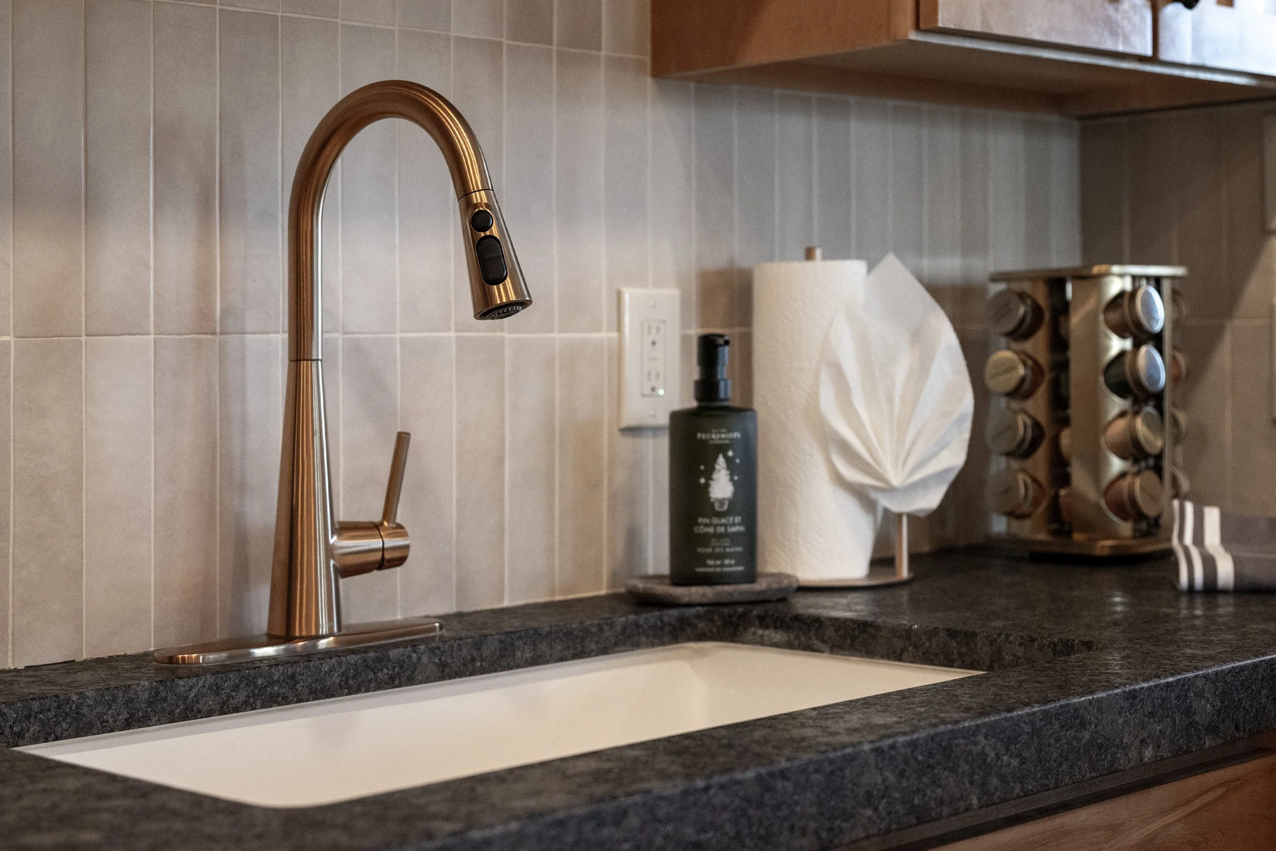 Modern bronze pull-down faucet and deep basin sink with dish soap and all the kitchen essentials you need for your stay.