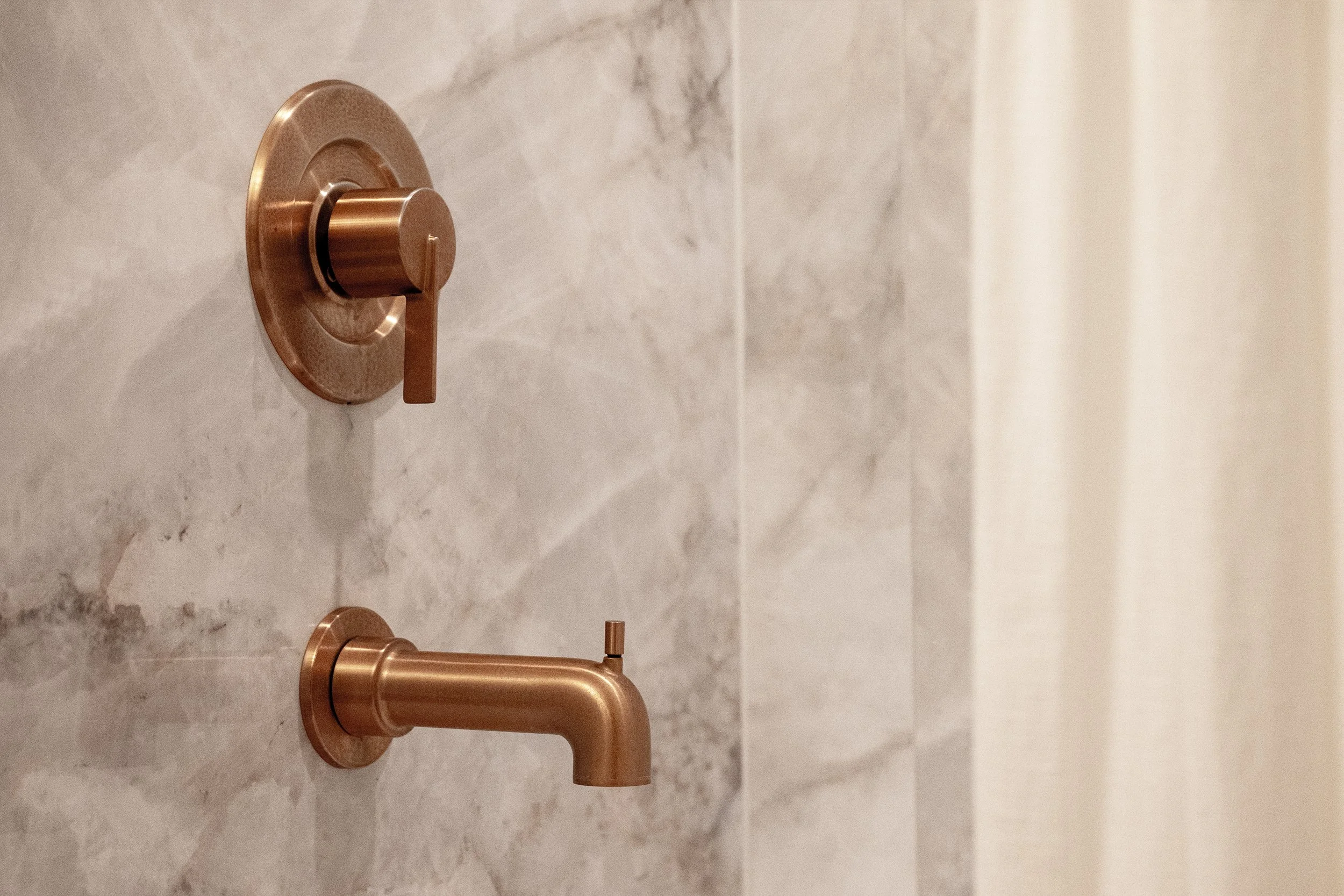 Sleek brushed-bronze shower fixtures add a modern, spa-like touch to the fully remodeled bathroom.