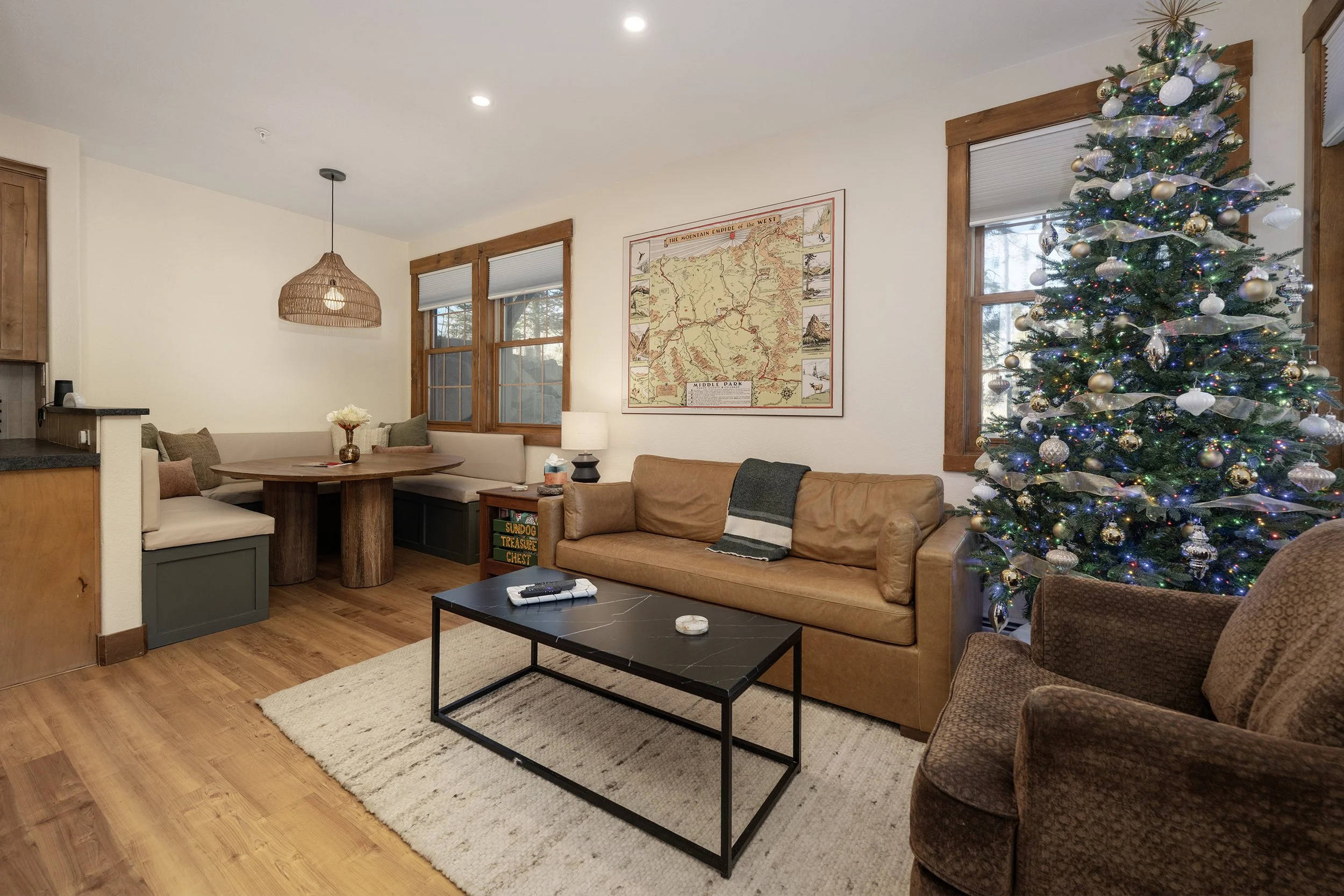 Cozy living and dining space with built-in banquette seating, leather sofa, and warm wood finishes - ideal for gathering after a day on the mountain.