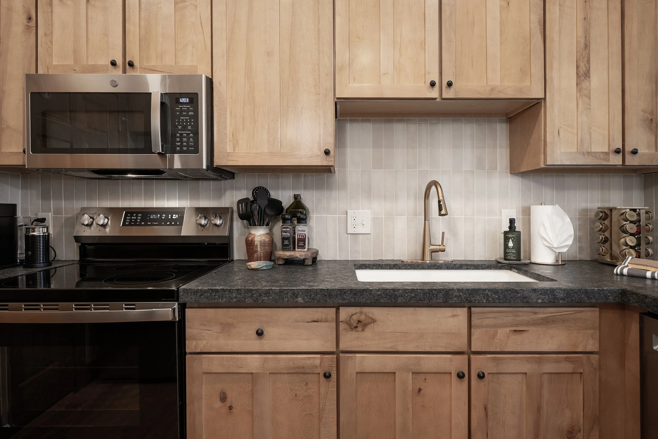 Bright, modern kitchen with upgraded appliances, wood cabinetry, granite countertops, and all the tools needed for home-cooked meals.