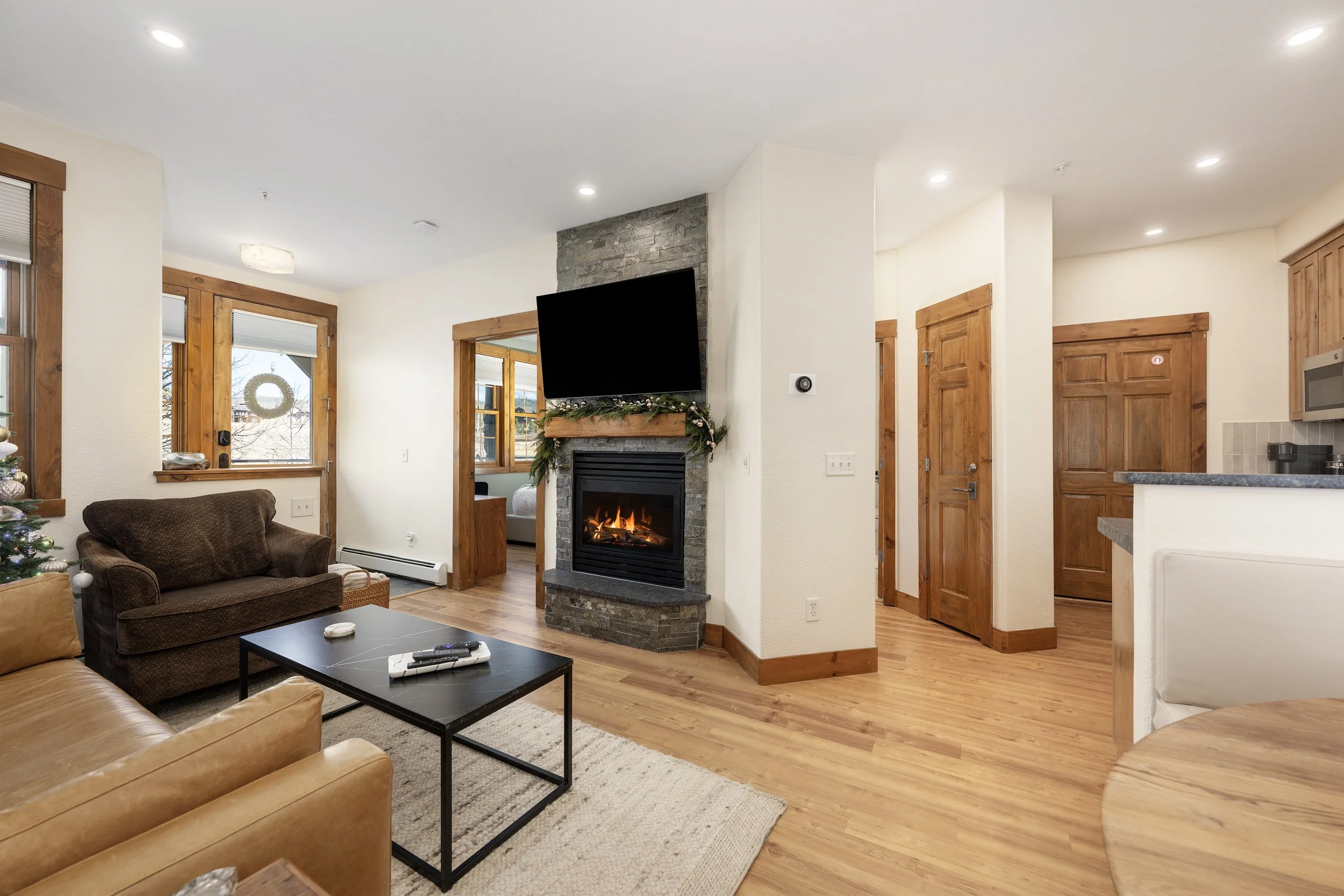 Cozy living room with a stone-framed gas fireplace, smart TV, and warm natural wood accents... wonderful for relaxing after a day on the mountain.