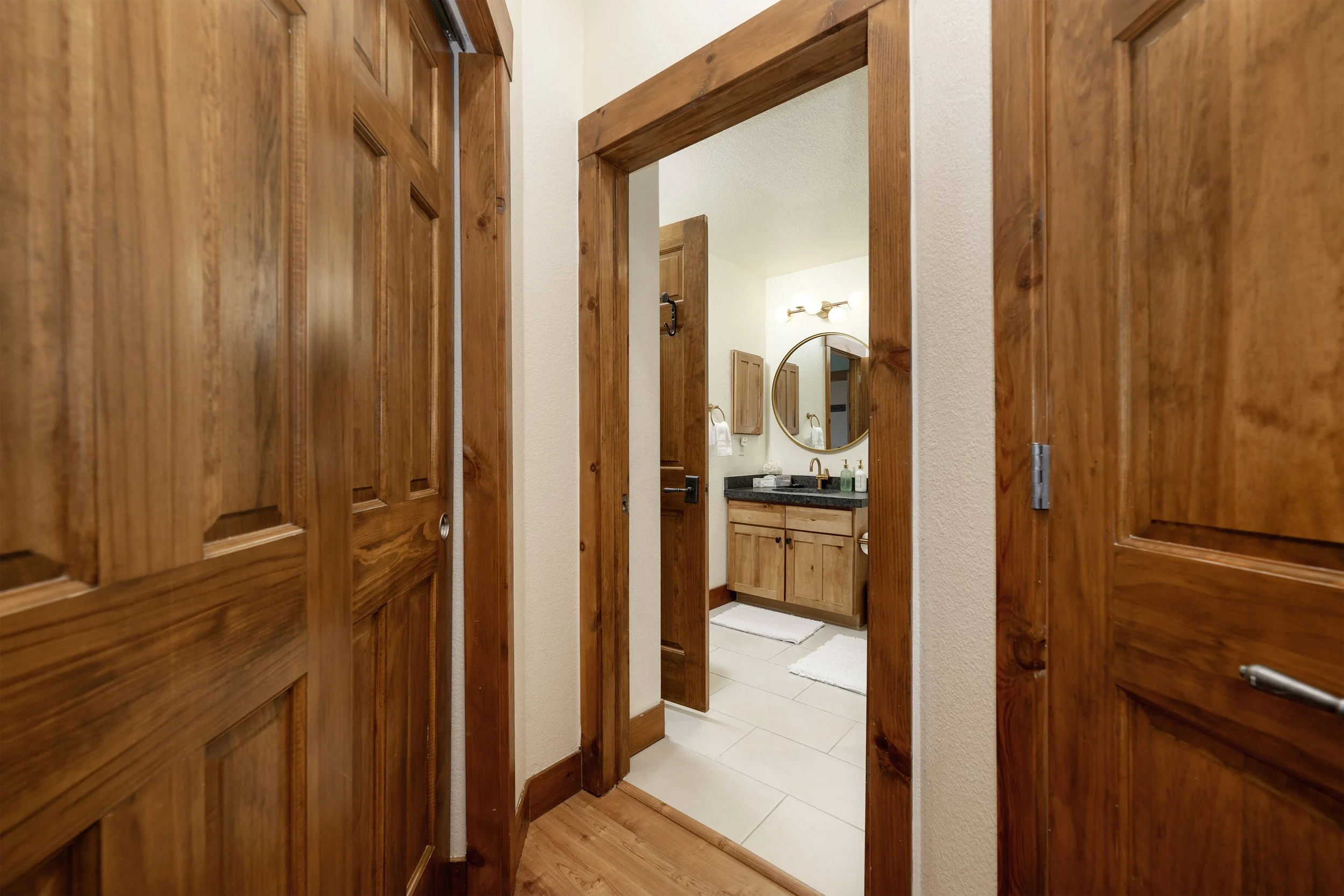 Warm hallway leading to the newly remodeled bathroom with natural wood doors and trim.