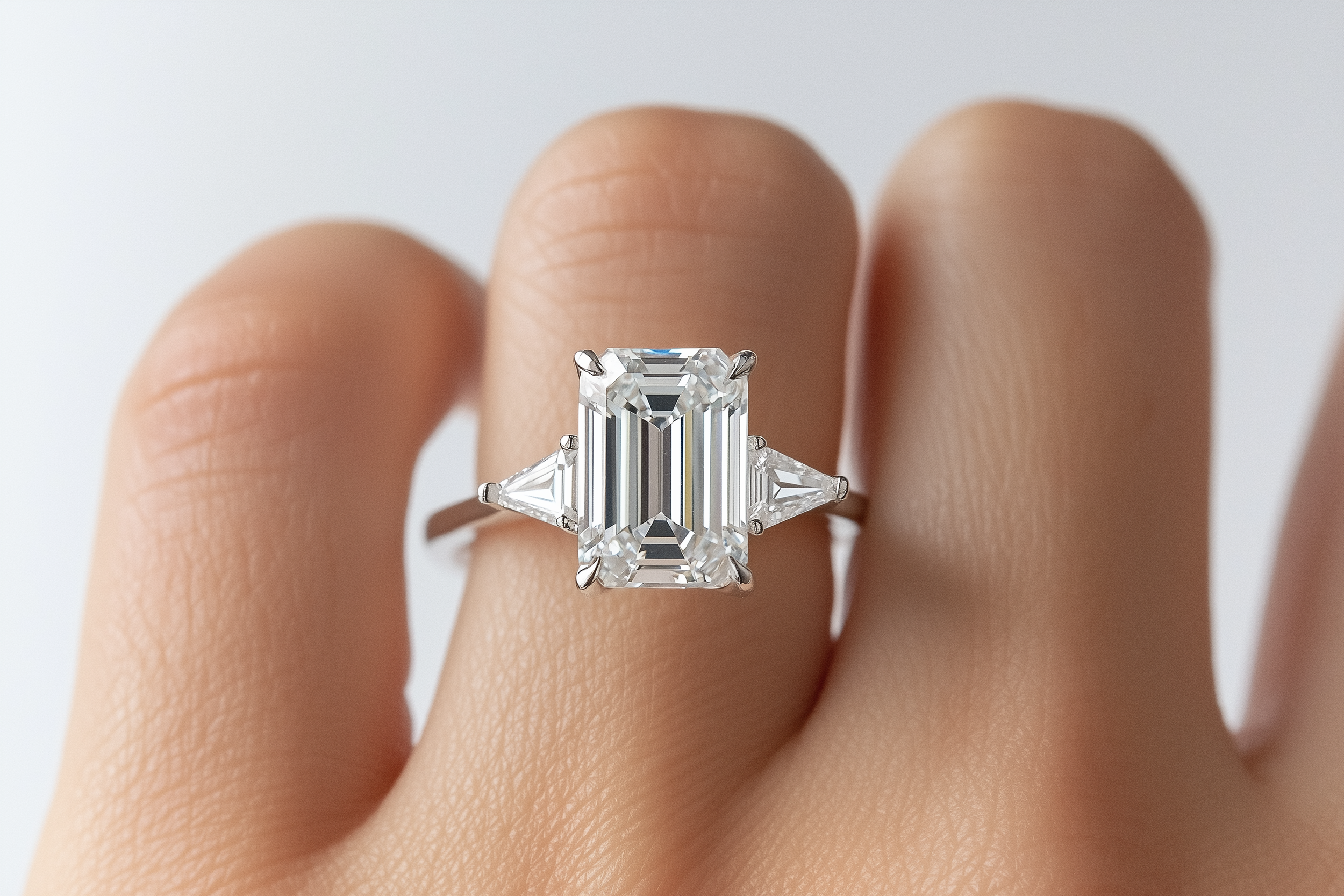 Nahaufnahme eines Diamantrings mit großem, rechteckigem Diamanten, getragen auf einem Finger mit heller Haut