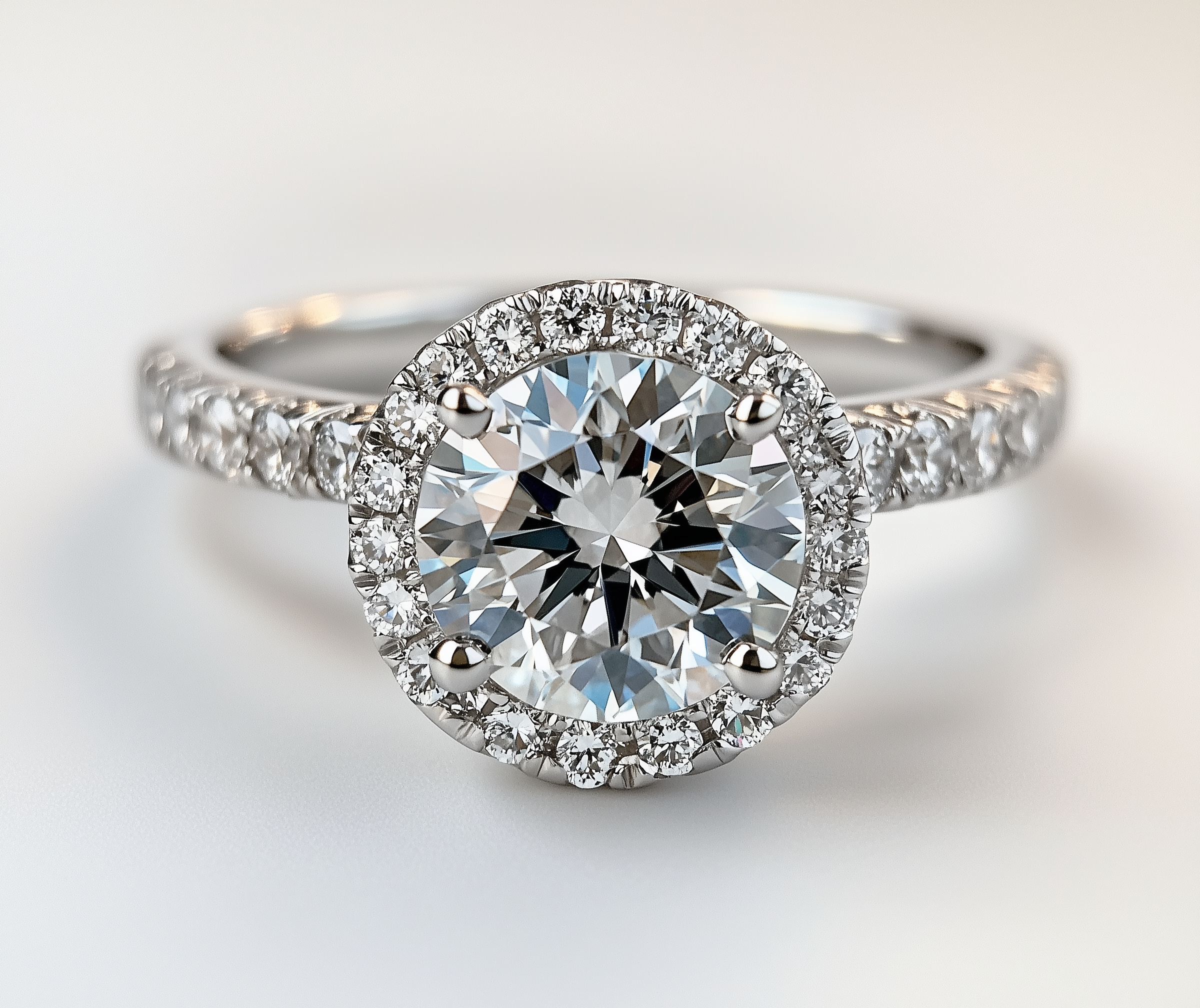 Ein silberner Verlobungsring mit einem großen zentralen Diamanten und umgebenden kleineren Diamanten auf weißem Hintergrund.