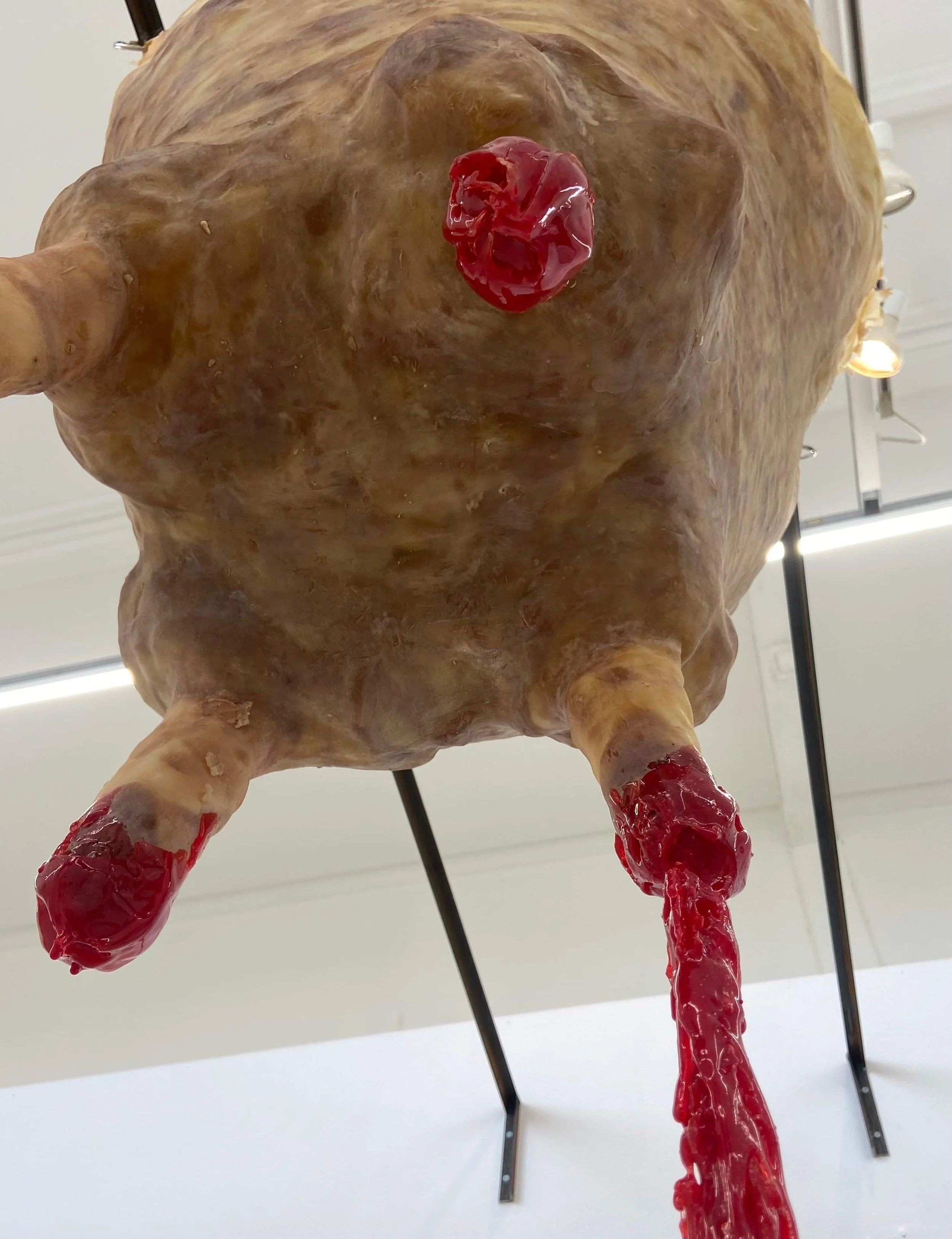 Artistic sculpture resembling an udder with red gelatinous substance.