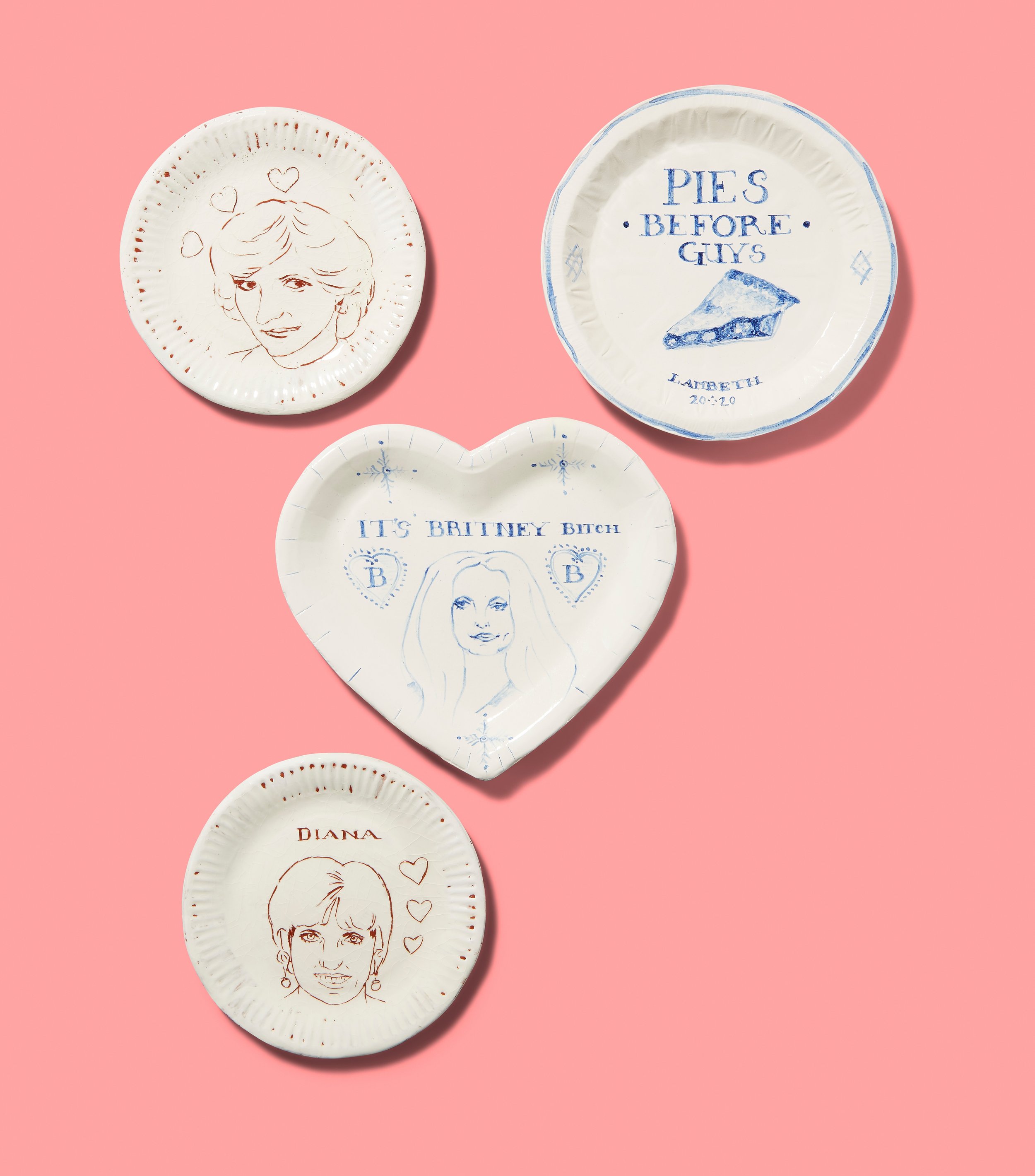 Four ceramic plates with hand-drawn designs of famous icons and text. One plate features "Pies Before Guys," another with a heart shape illustrating "It's Britney Bitch." Two plates show portraits labeled "Diana" with hearts.