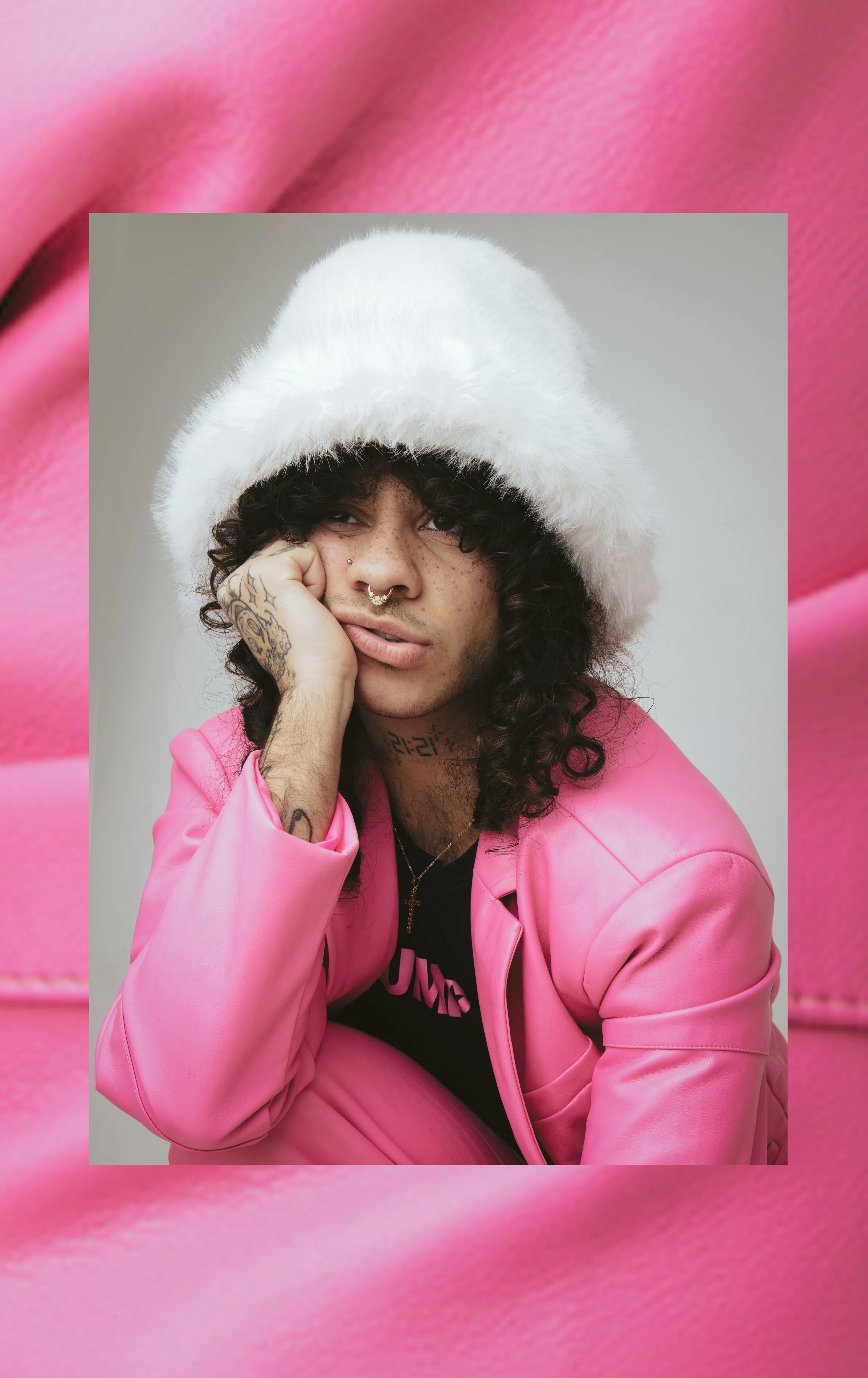 Person wearing a white furry hat and pink suit against a pink background.