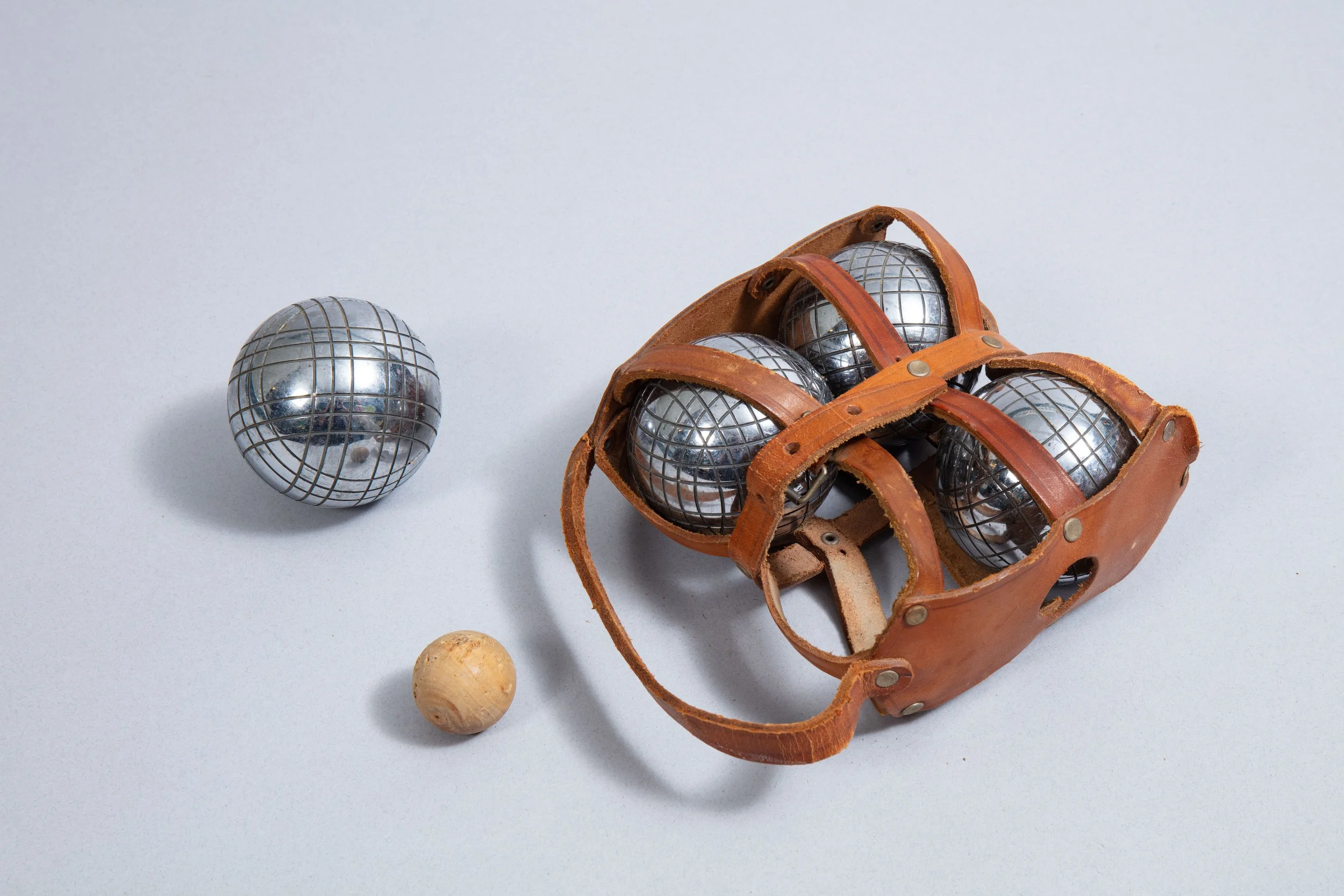A set of four pétanque balls in a leather case with the jack made of wood