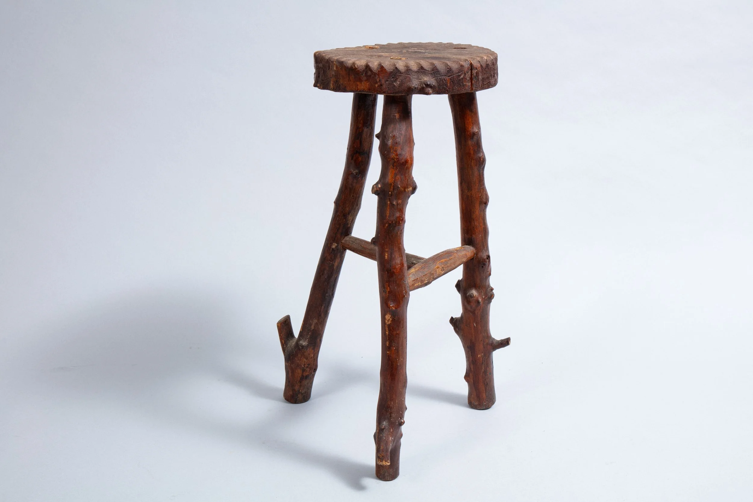Tall folk-art-style three-legged stool.