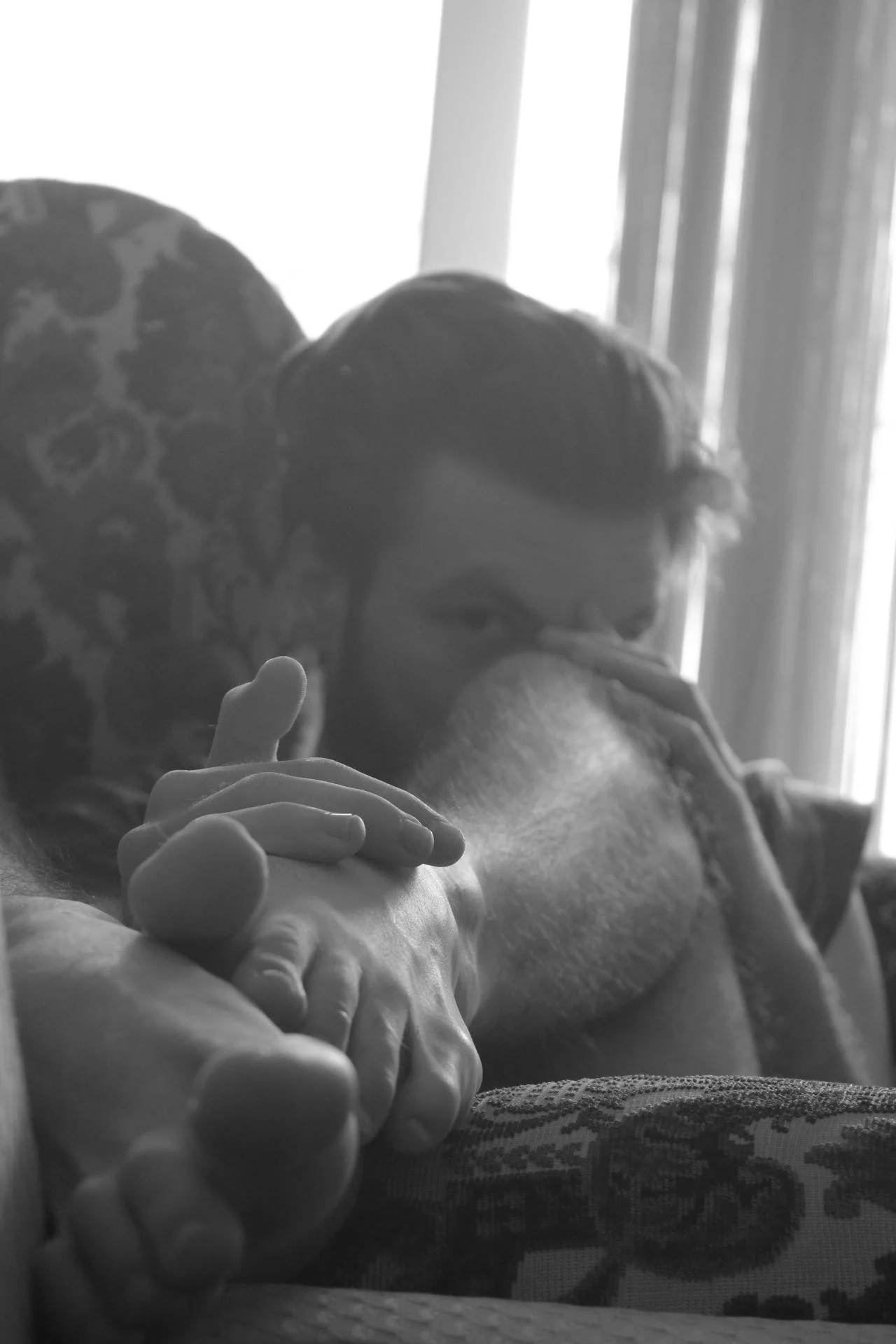 A black and white photo showing a young white man on an armchair