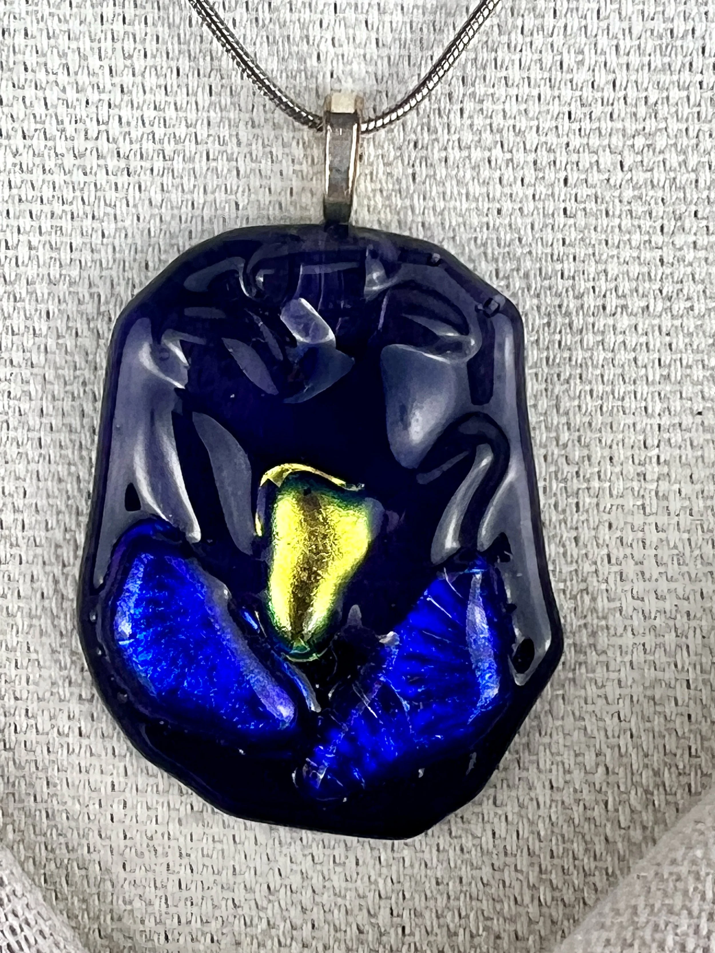 Close-up of vibrant blue and dichroic glass pendant showing iridescent details