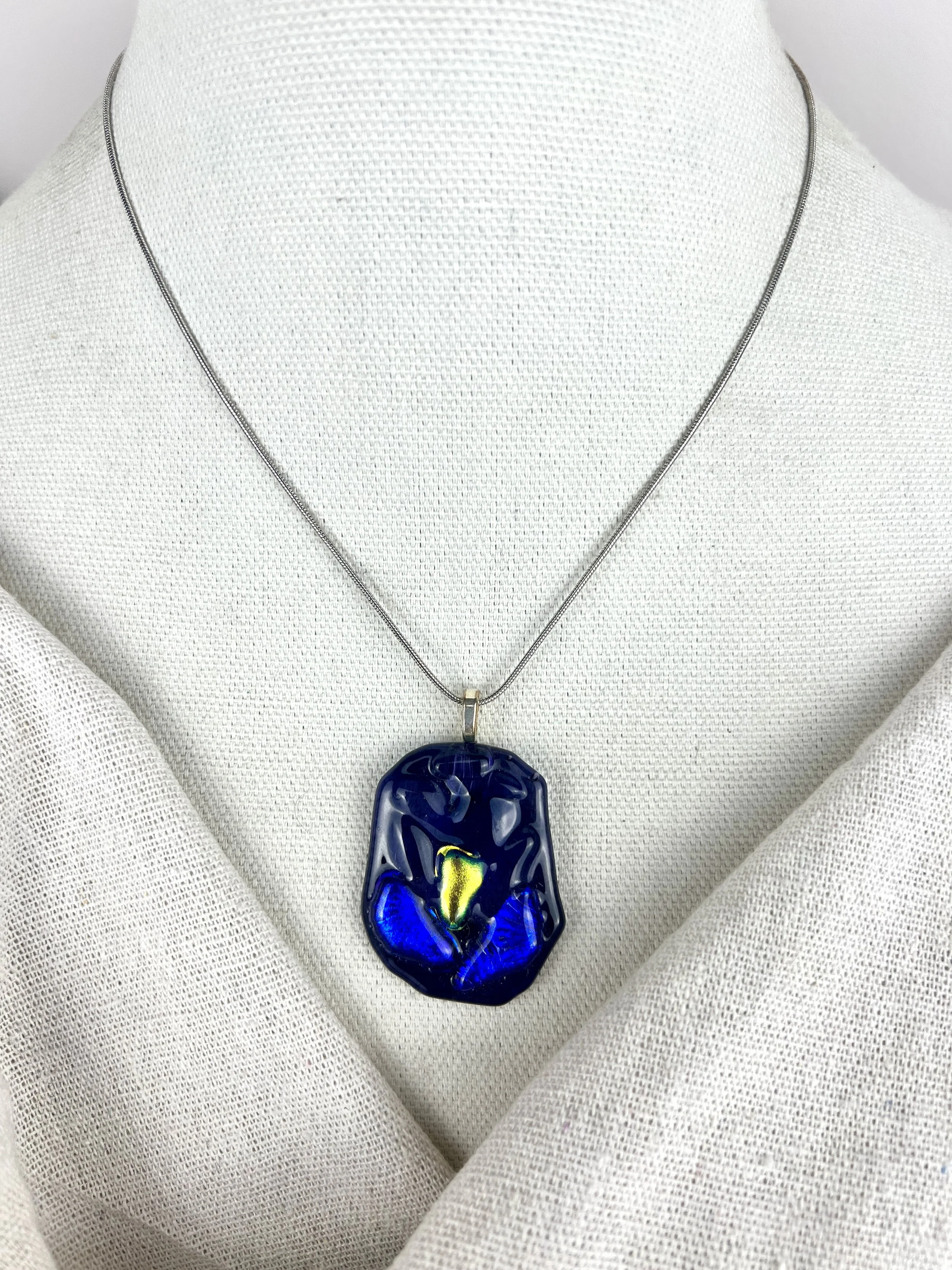 Handcrafted dichroic midnight glass pendant with gold-green shifting center on silver snake chain