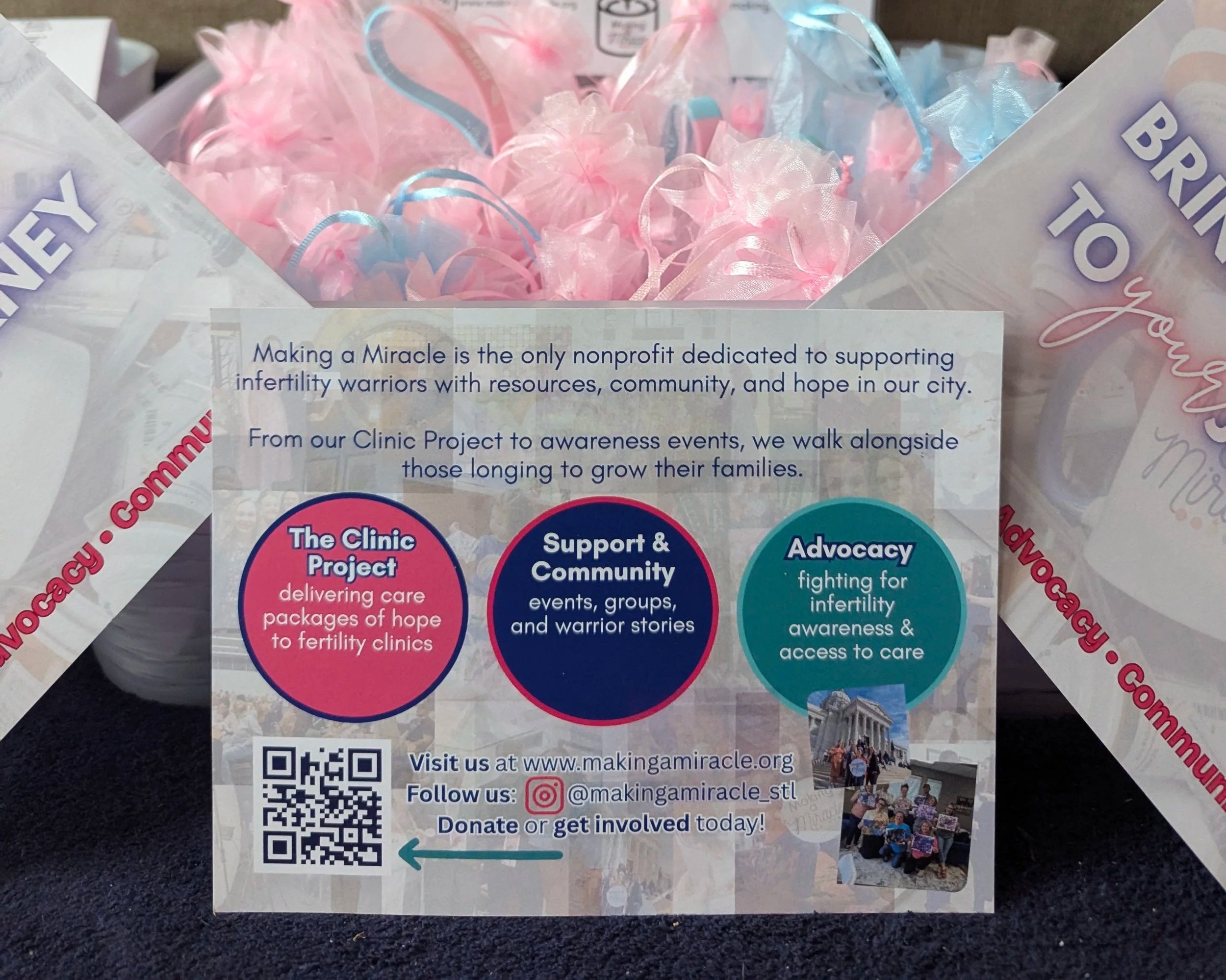 A flyer from Making a Miracle nonprofit organization with pink and blue decorative ribbon-like material inside a transparent bag. The flyer promotes the organization's services, events, and ways to get involved, with a QR code, website, and social media handles at the bottom.
