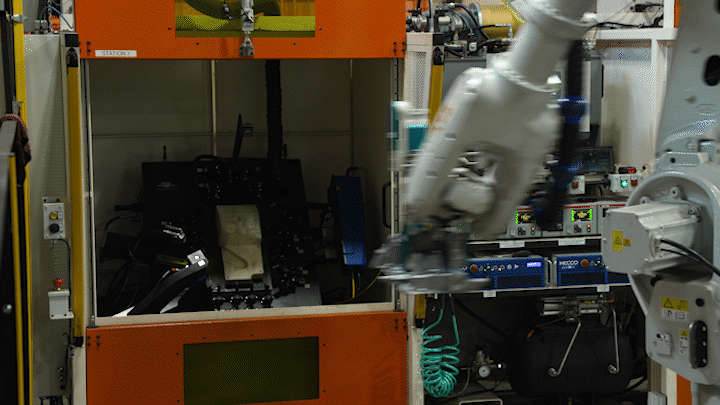 A robotic arm working in a laboratory environment with various equipment and machinery.