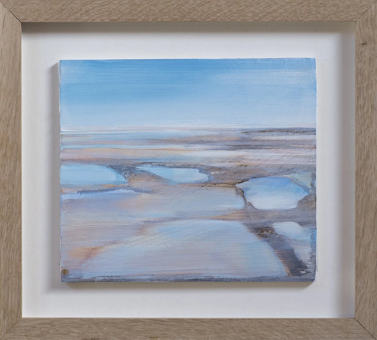 A painting of a landscape with water, rocks, and a blue sky, framed in light wood.