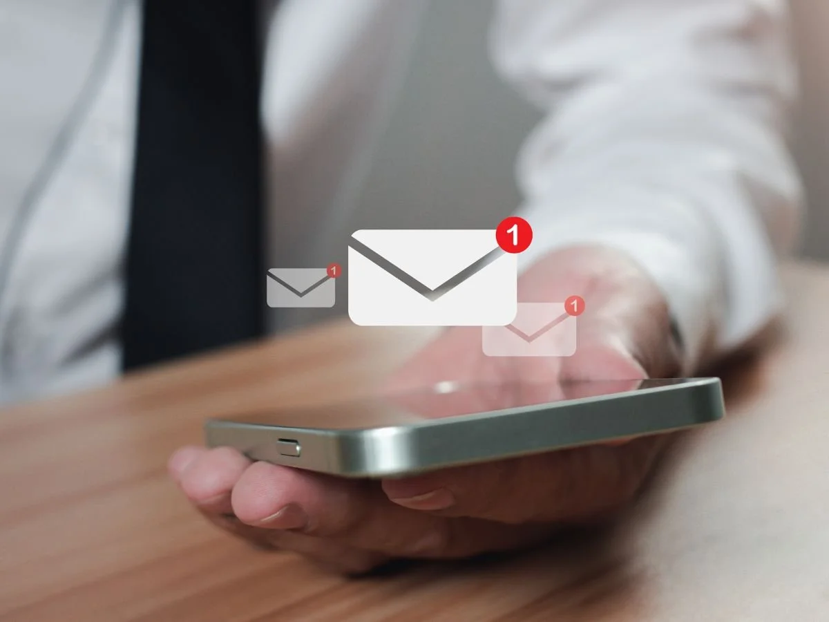 A person holding a smartphone with email notification icons, symbolizing email marketing and lead generation strategies.