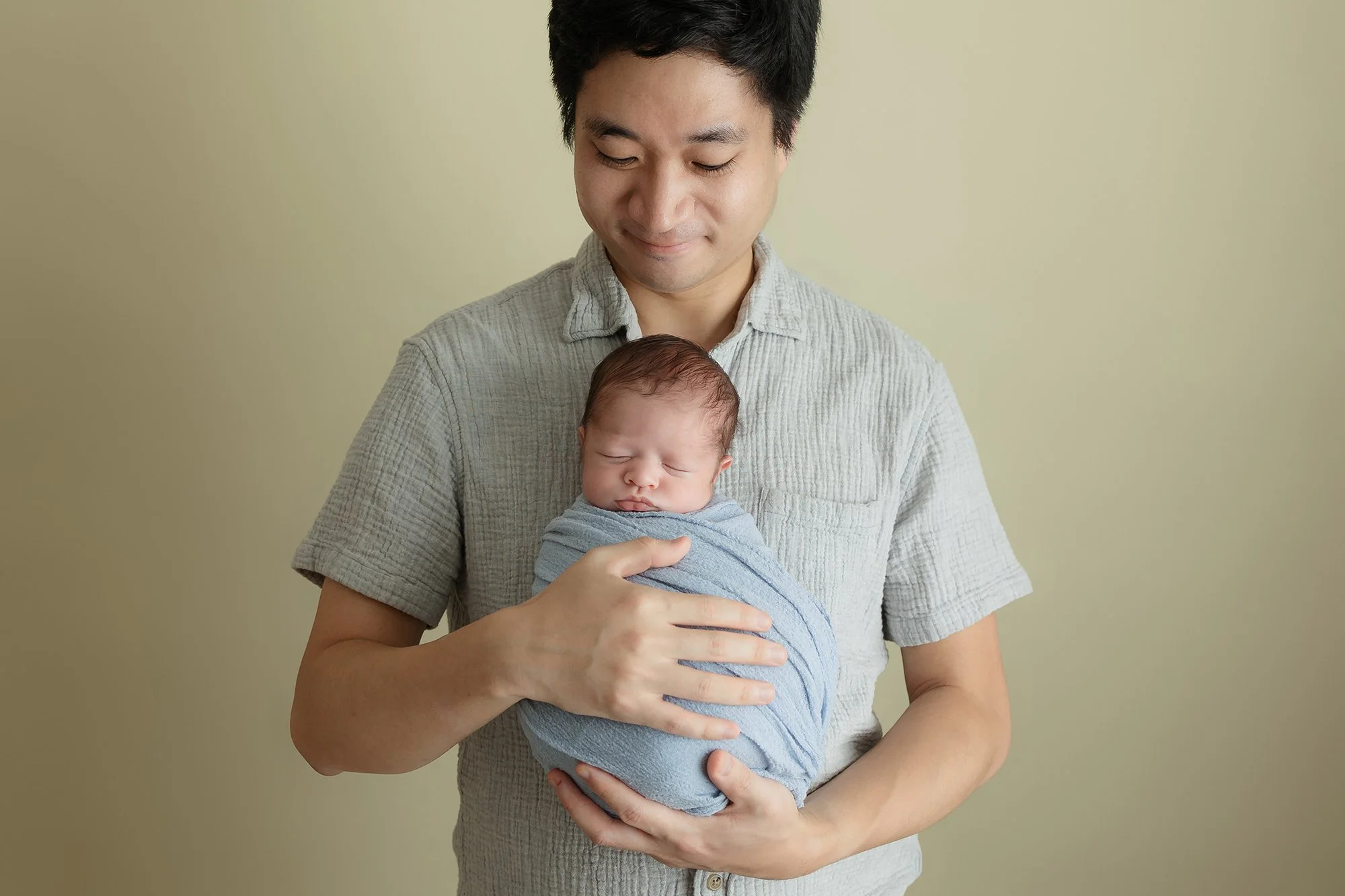 Loving father posing with his newborn son in my studio.