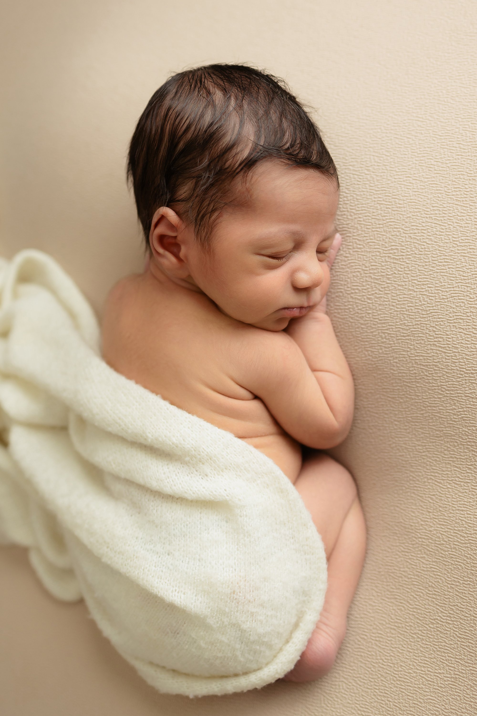 Cute baby curled up for his first newborn photos.
