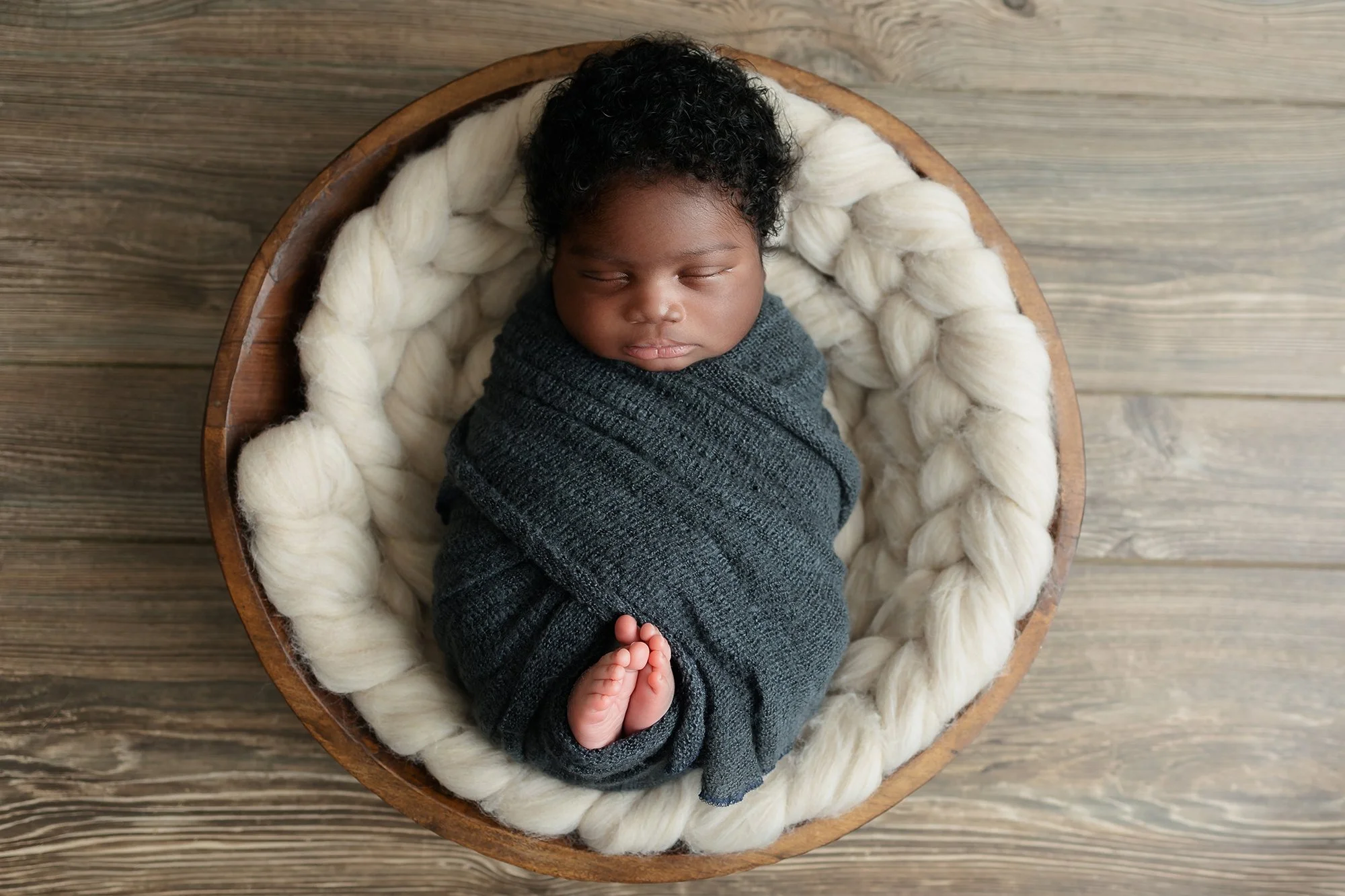 baby boy posing in bucket for his newborn photography session in manassas Virginia studio.