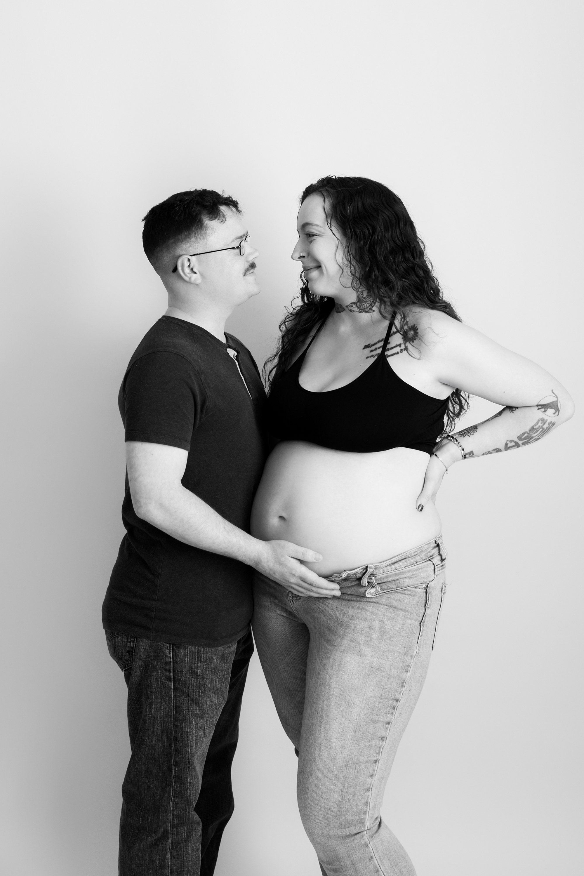 Maternity photo of a mother-to-be with her husband posing in a studio setting in Independent Hill.