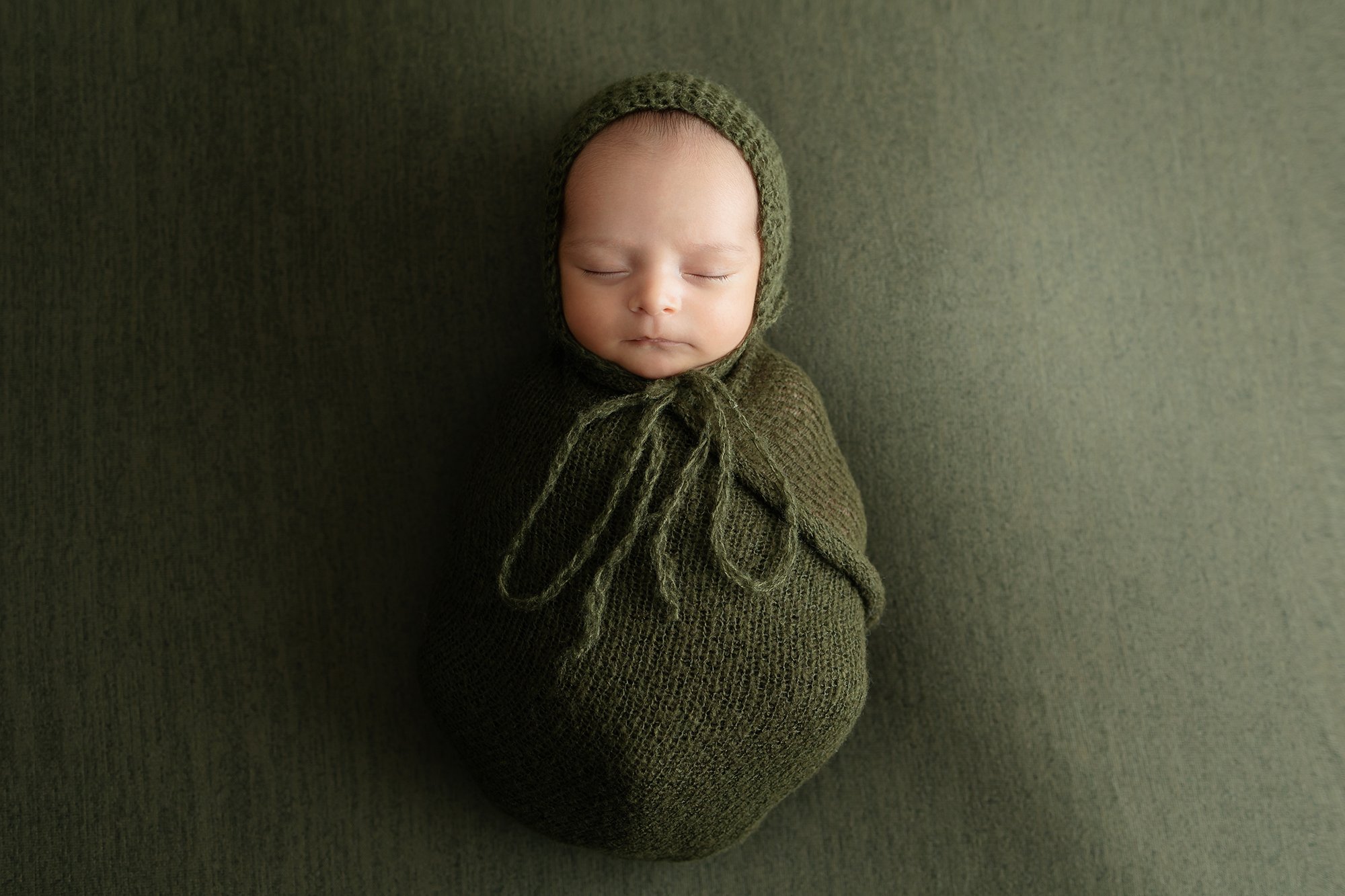 Newborn baby boy posing on blanket for photography session