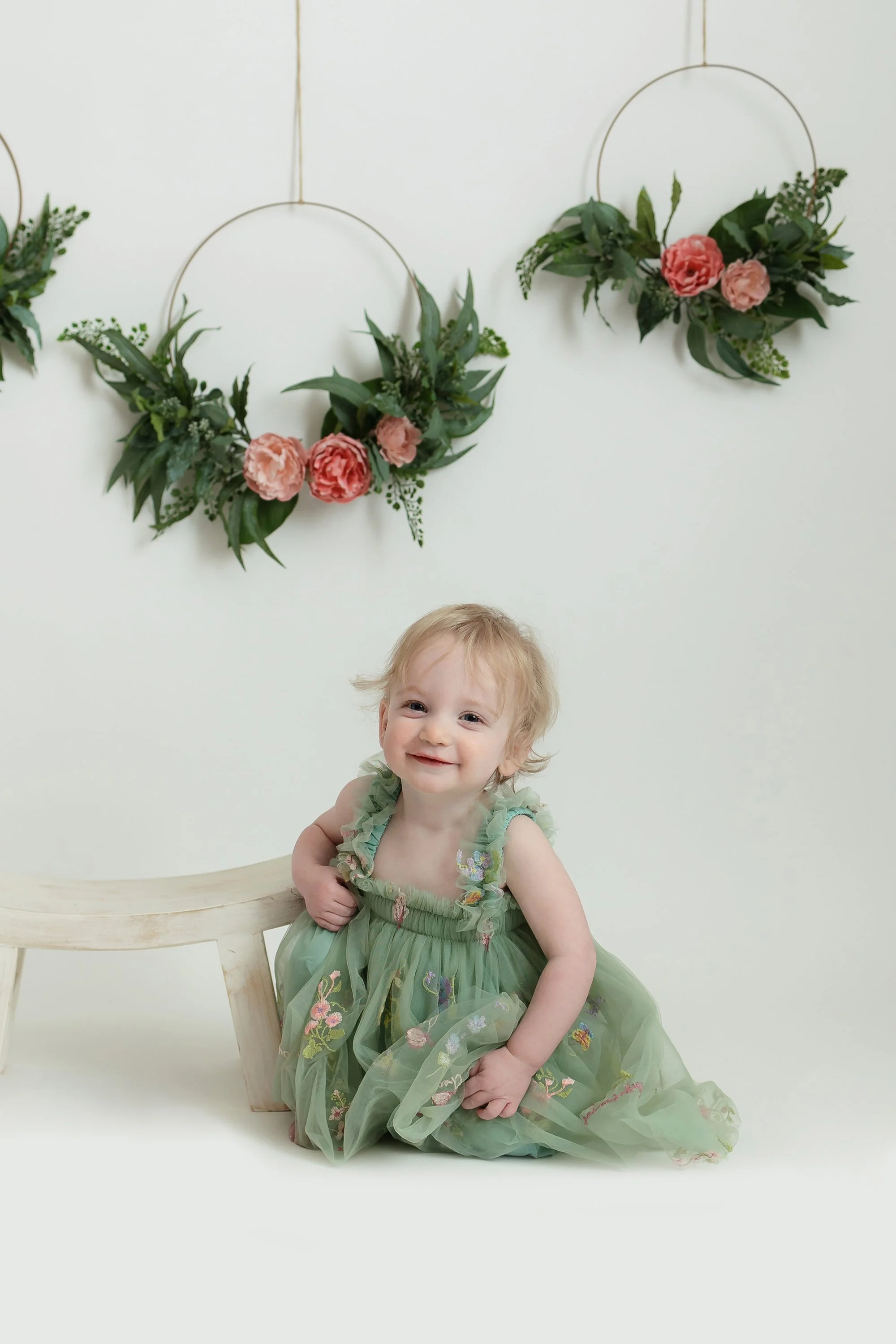 Milestone portrait of one year old baby posing next to a stool.