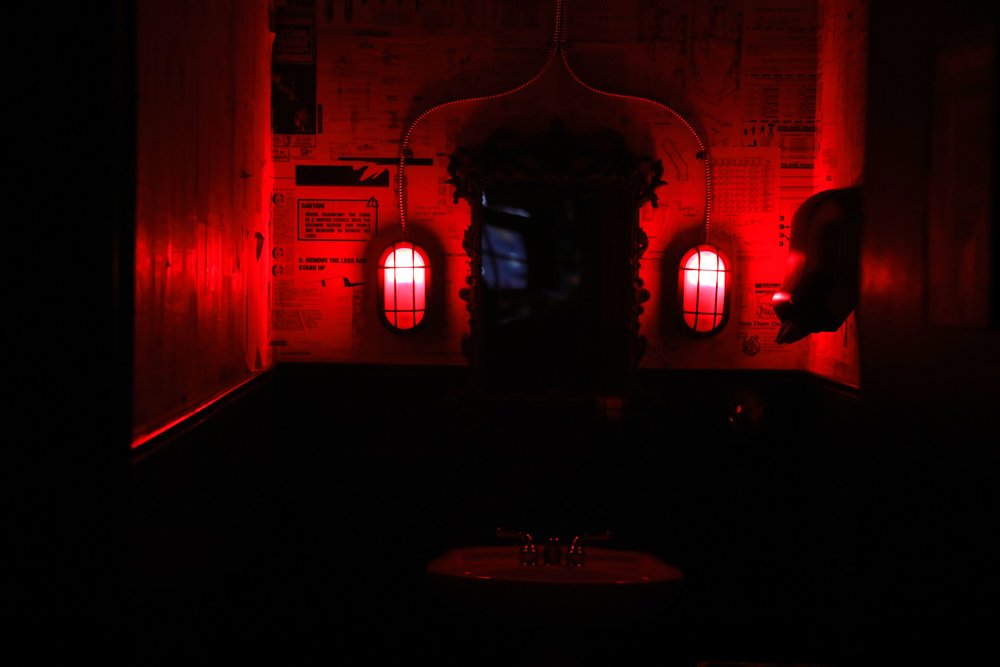 The red-lit bathroom of the Racket Bar &amp; Pinball Lounge