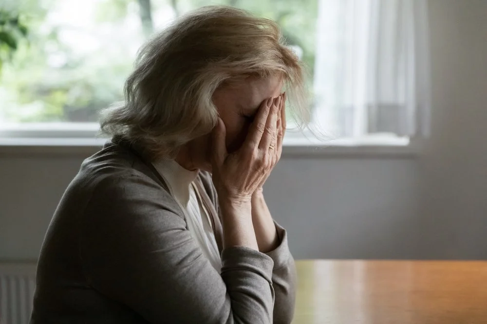 An older adult woman crying with her face in her hands | Safer Sacramento
