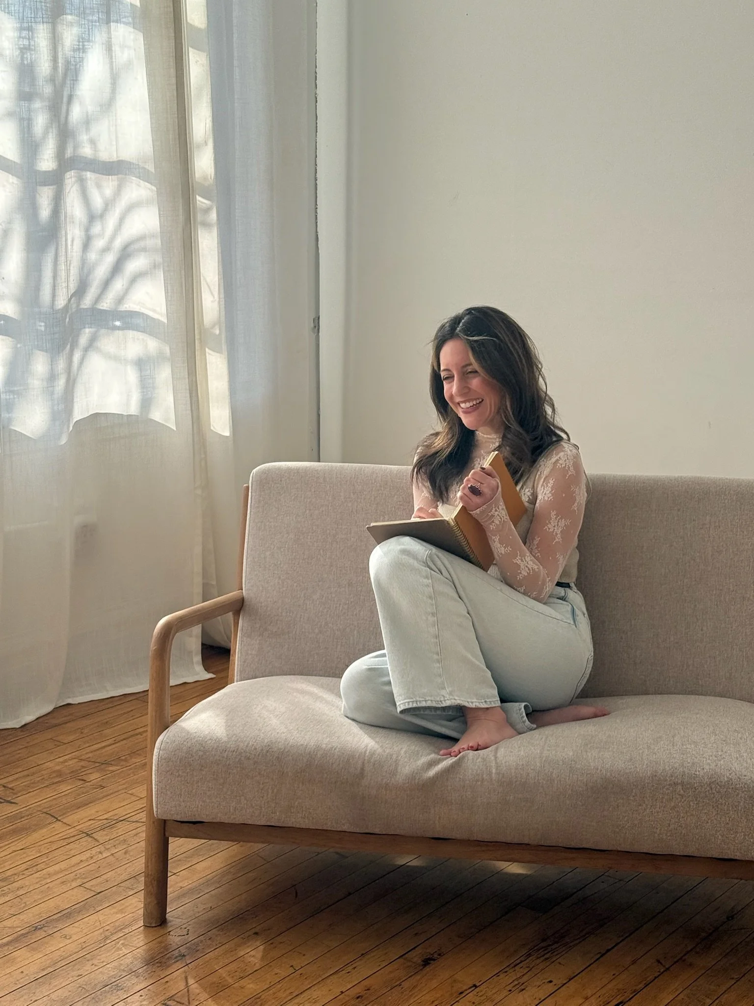Dana Marie Gatziolis, Founder of The Poetry Apothecary, sitting in a loft, writing, smiling