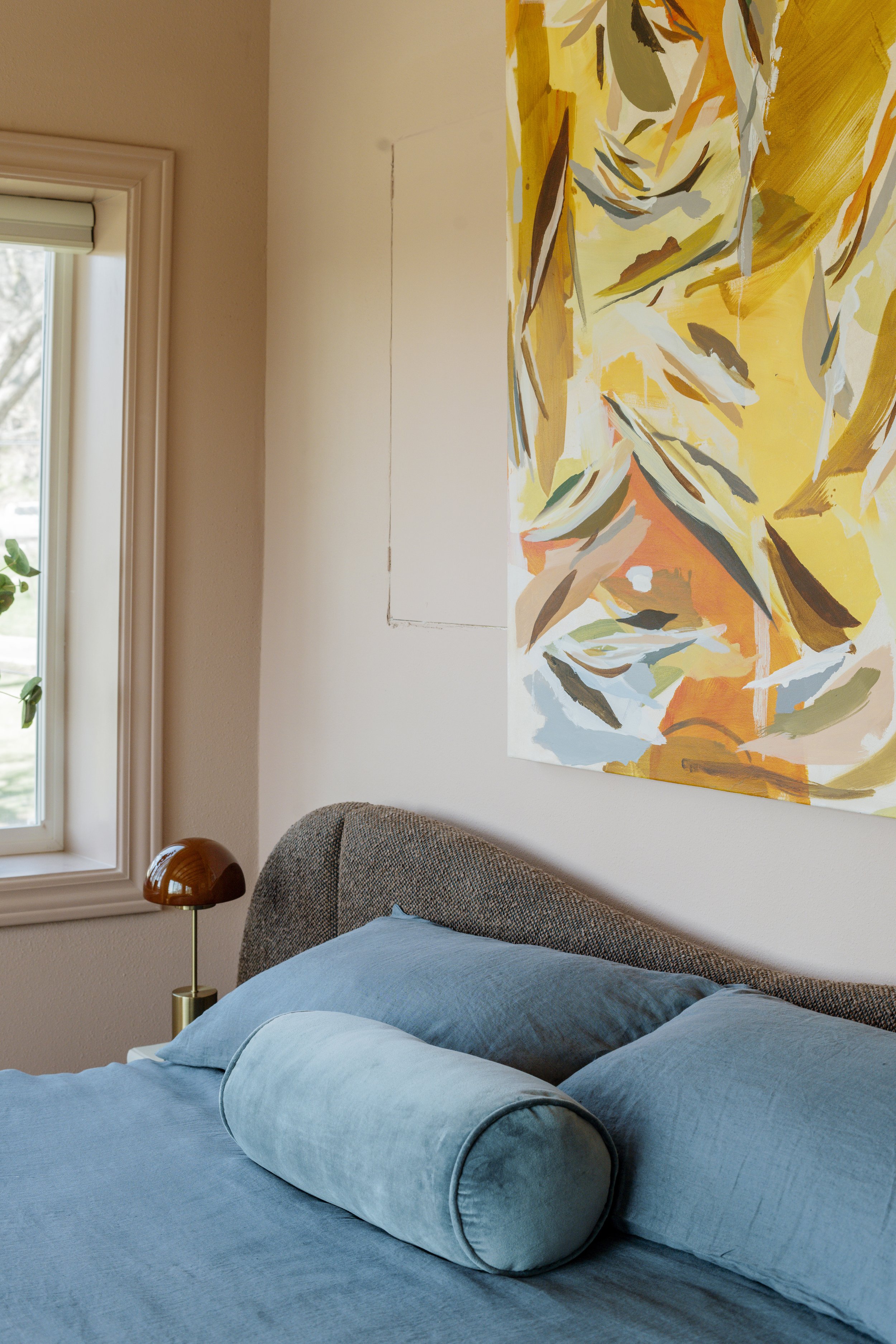 Dusty blue bedding and pillows that are accented with the colors in the artwork so beautifully